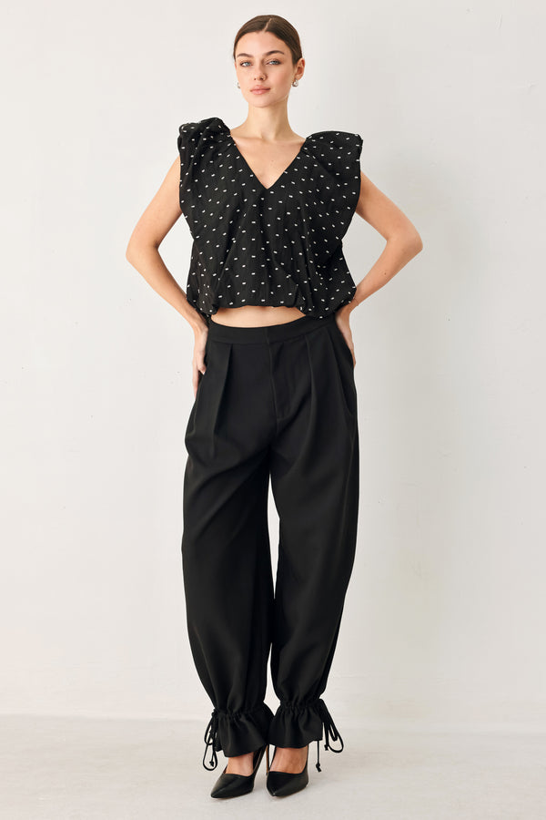 Woman wearing a black polka dot top featuring V neckline with bubble sleeve and waist | FREEMARKET