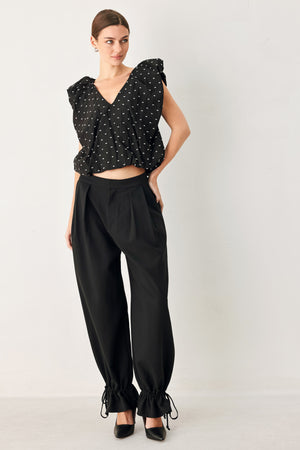Woman wearing a black polka dot top featuring V neckline with bubble sleeve and waist | FREEMARKET