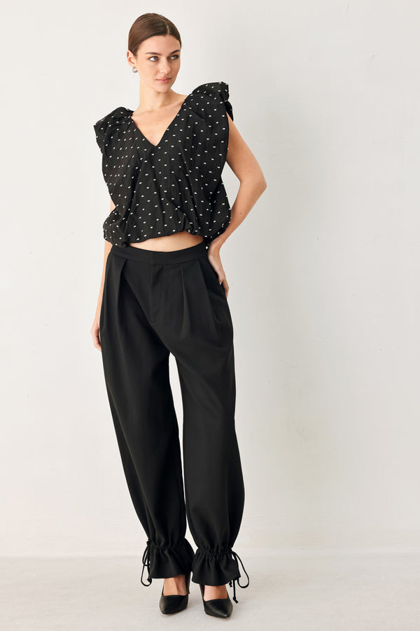 Woman wearing a black polka dot top featuring V neckline with bubble sleeve and waist | FREEMARKET