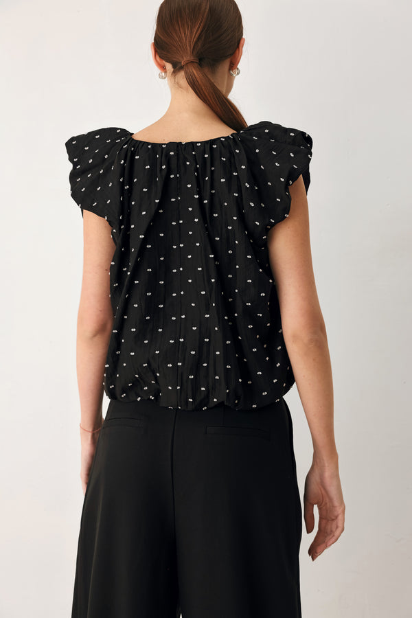 Woman wearing a black polka dot top featuring V neckline with bubble sleeve and waist | FREEMARKET