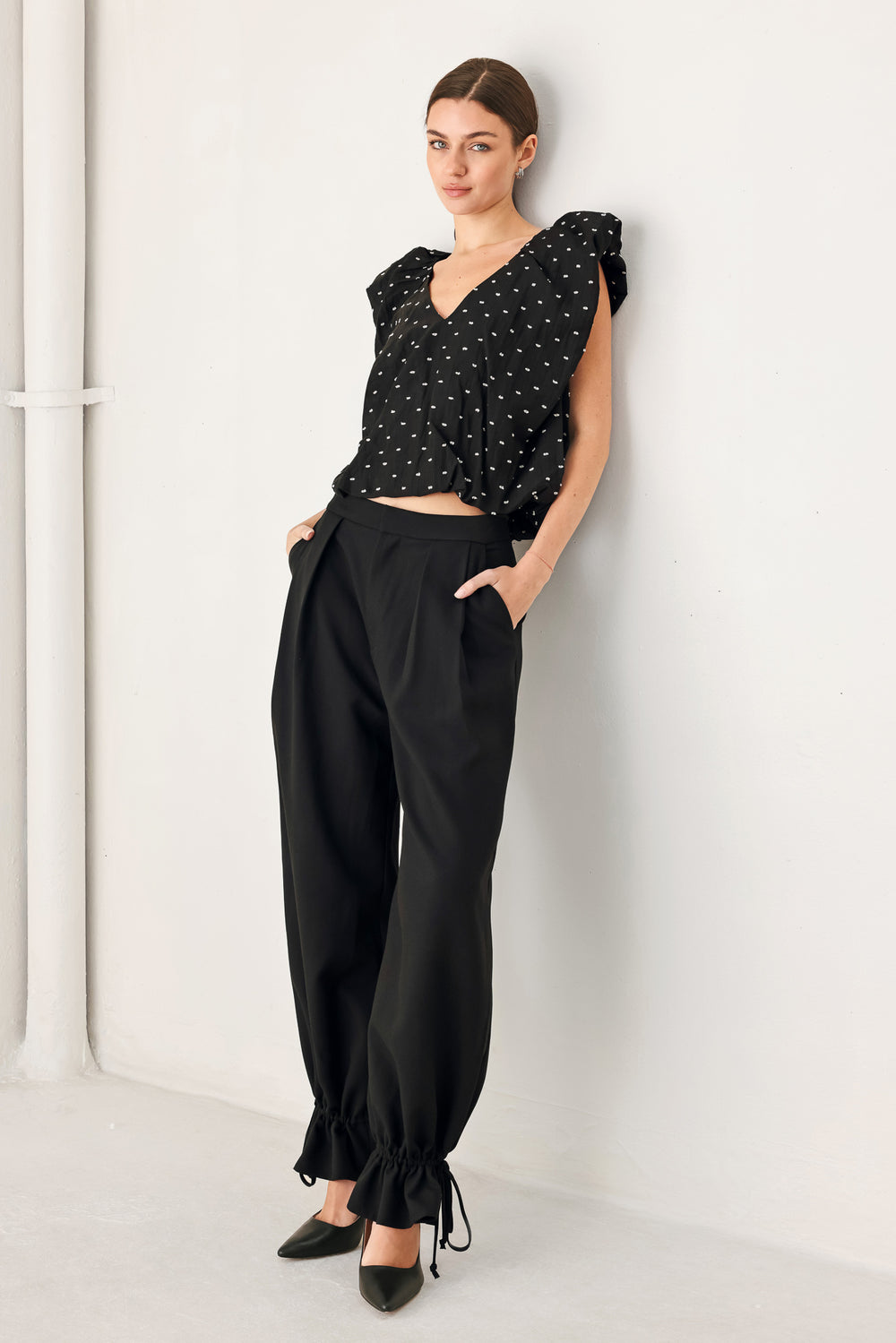 Woman wearing a black polka dot top featuring V neckline with bubble sleeve and waist | FREEMARKET