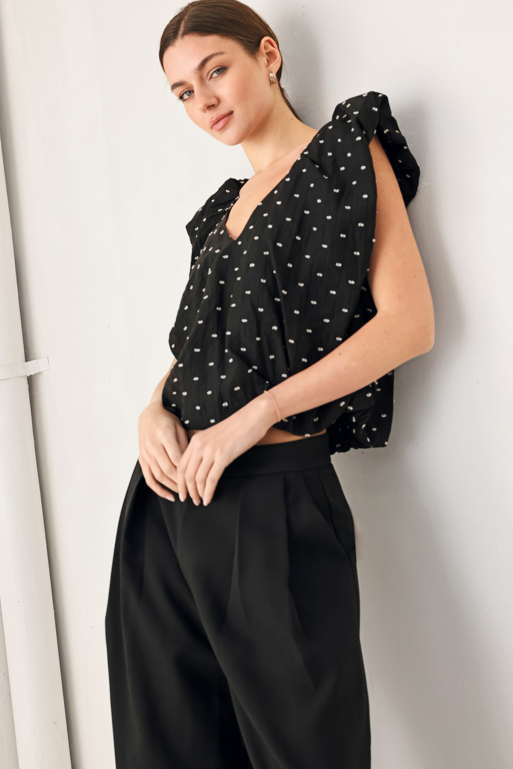 Woman wearing a black polka dot top featuring V neckline with bubble sleeve and waist | FREEMARKET