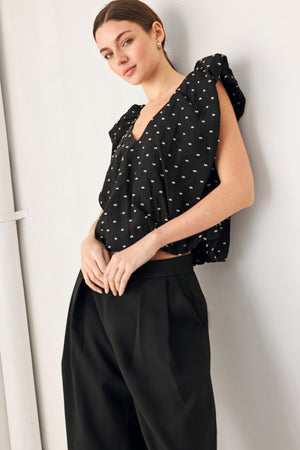 Woman wearing a black polka dot top featuring V neckline with bubble sleeve and waist | FREEMARKET