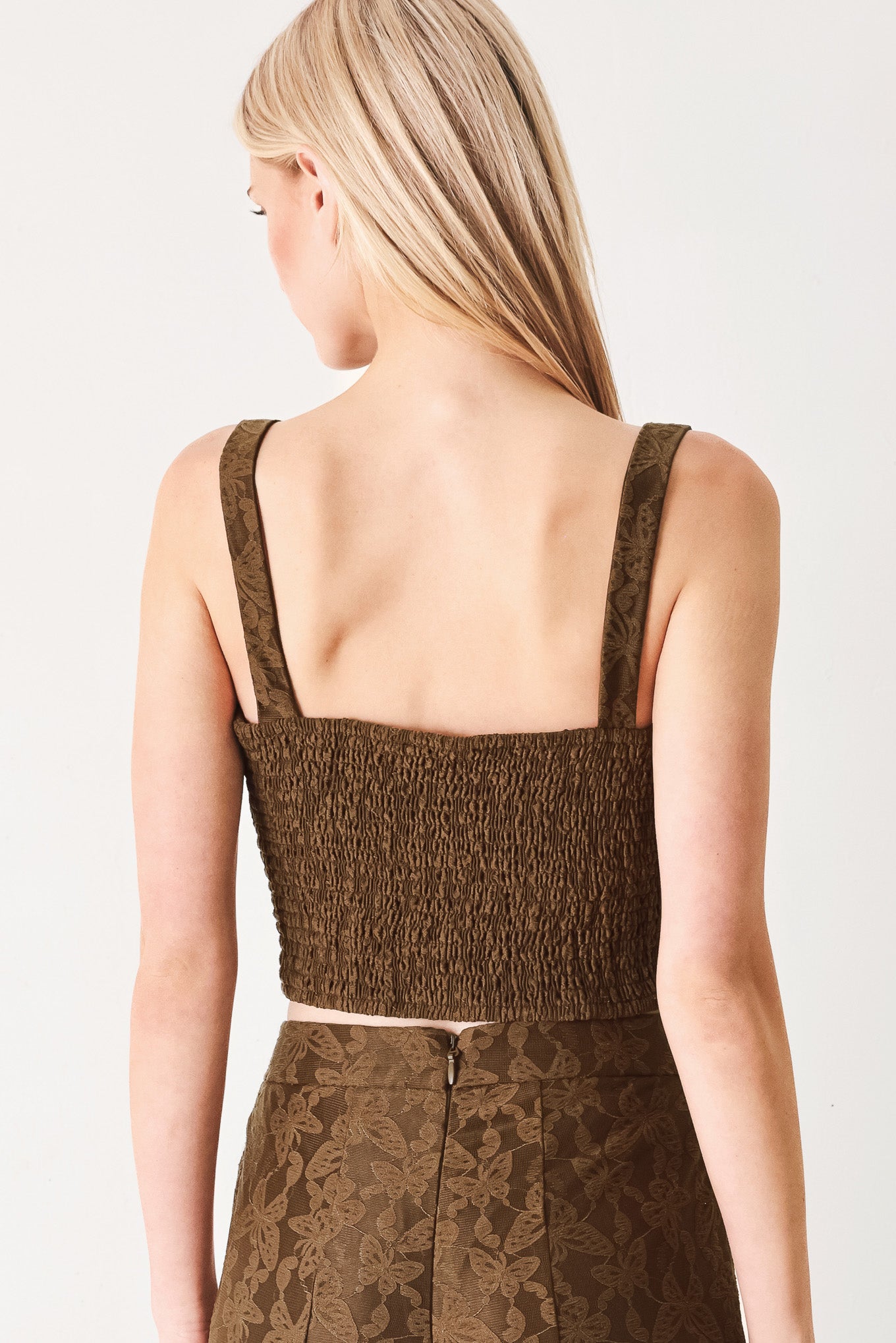 Woman wearing a brown crop top with front button detail and smocked back bodice | FREEMARKET