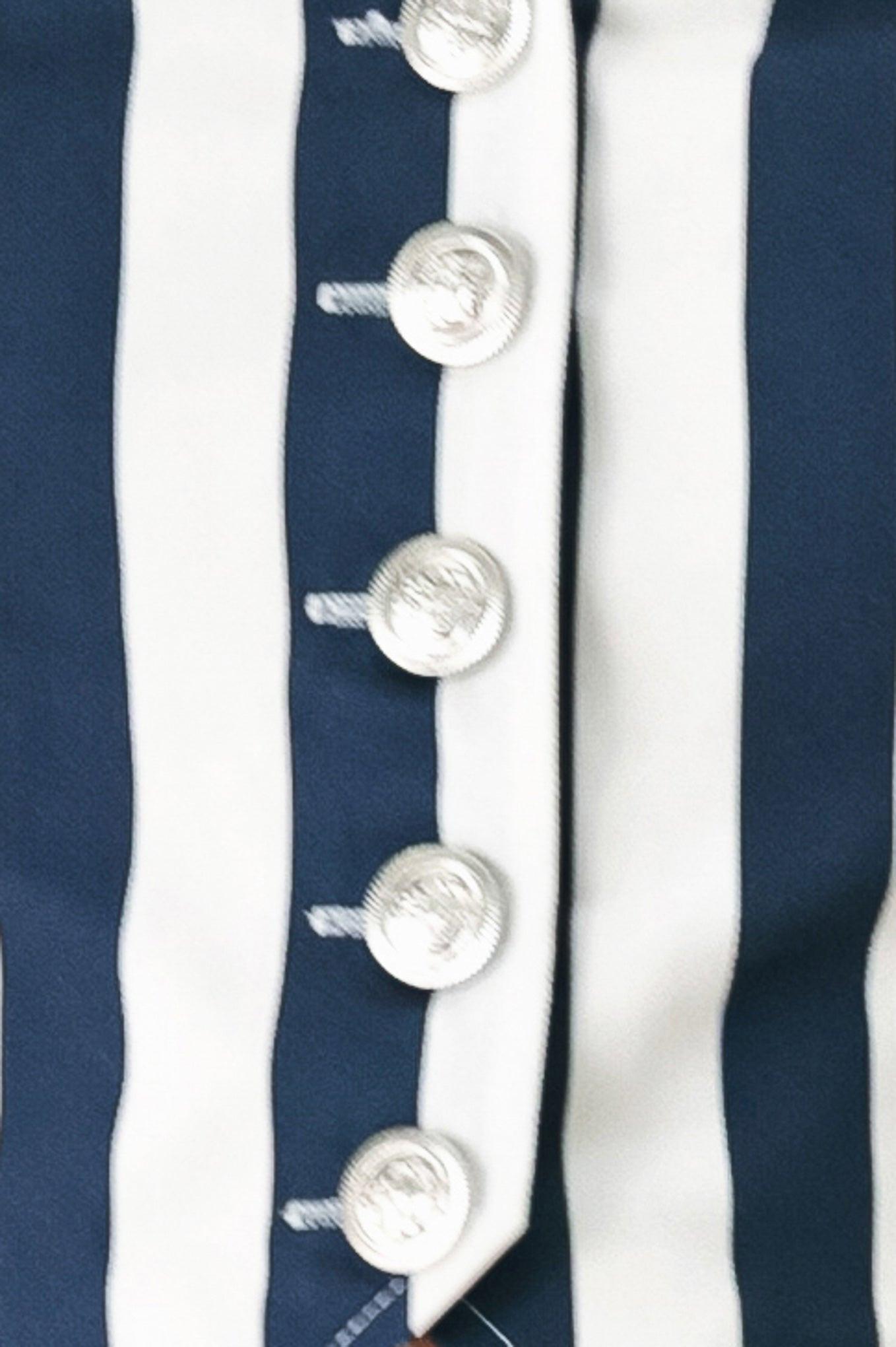 Close-up of a navy and white striped fabric with silver buttons.