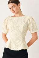 Woman wearing a white lace jacquard top featuring round neckline, short sleeve, peplum and V back with zipper closure | FREEMARKET