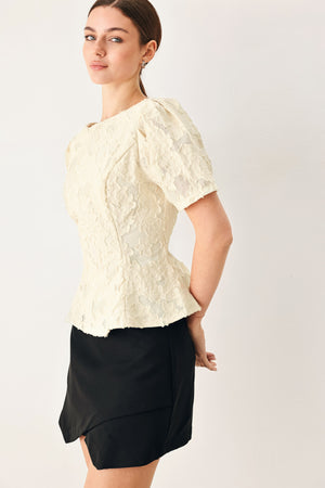 Woman wearing a white lace jacquard top featuring round neckline, short sleeve, peplum and V back with zipper closure | FREEMARKET