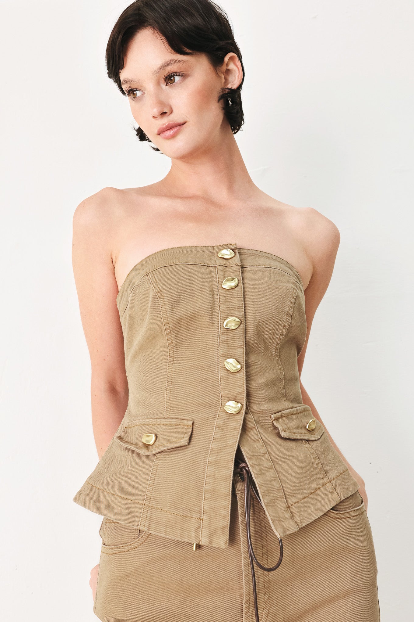 Woman wearing a khaki strapless tube top with front button detail and back zipper closure | FREEMARKET