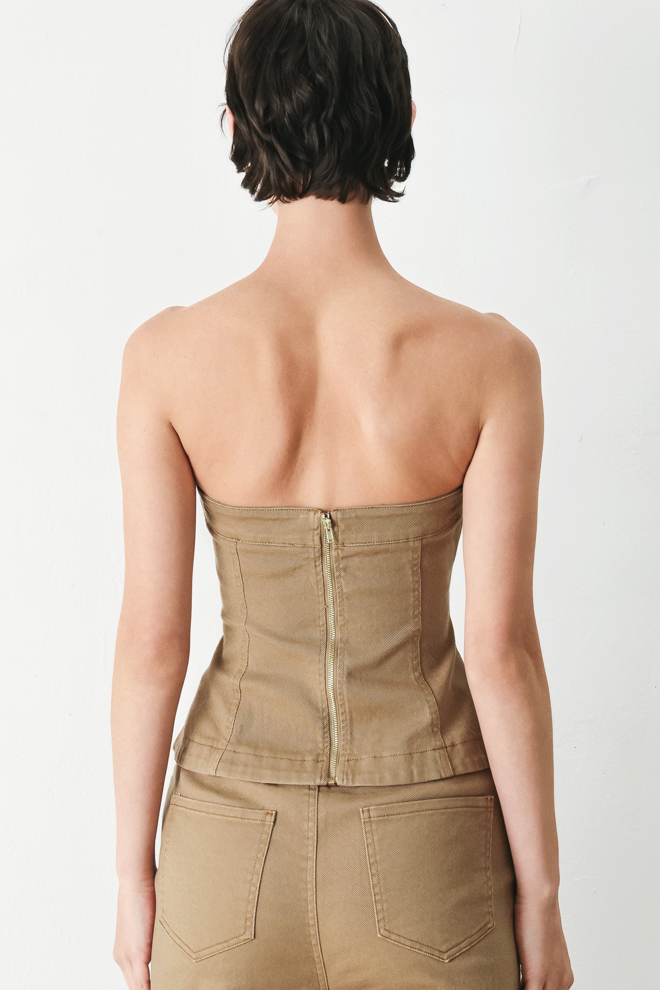 Woman wearing a khaki strapless tube top with front button detail and back zipper closure | FREEMARKET