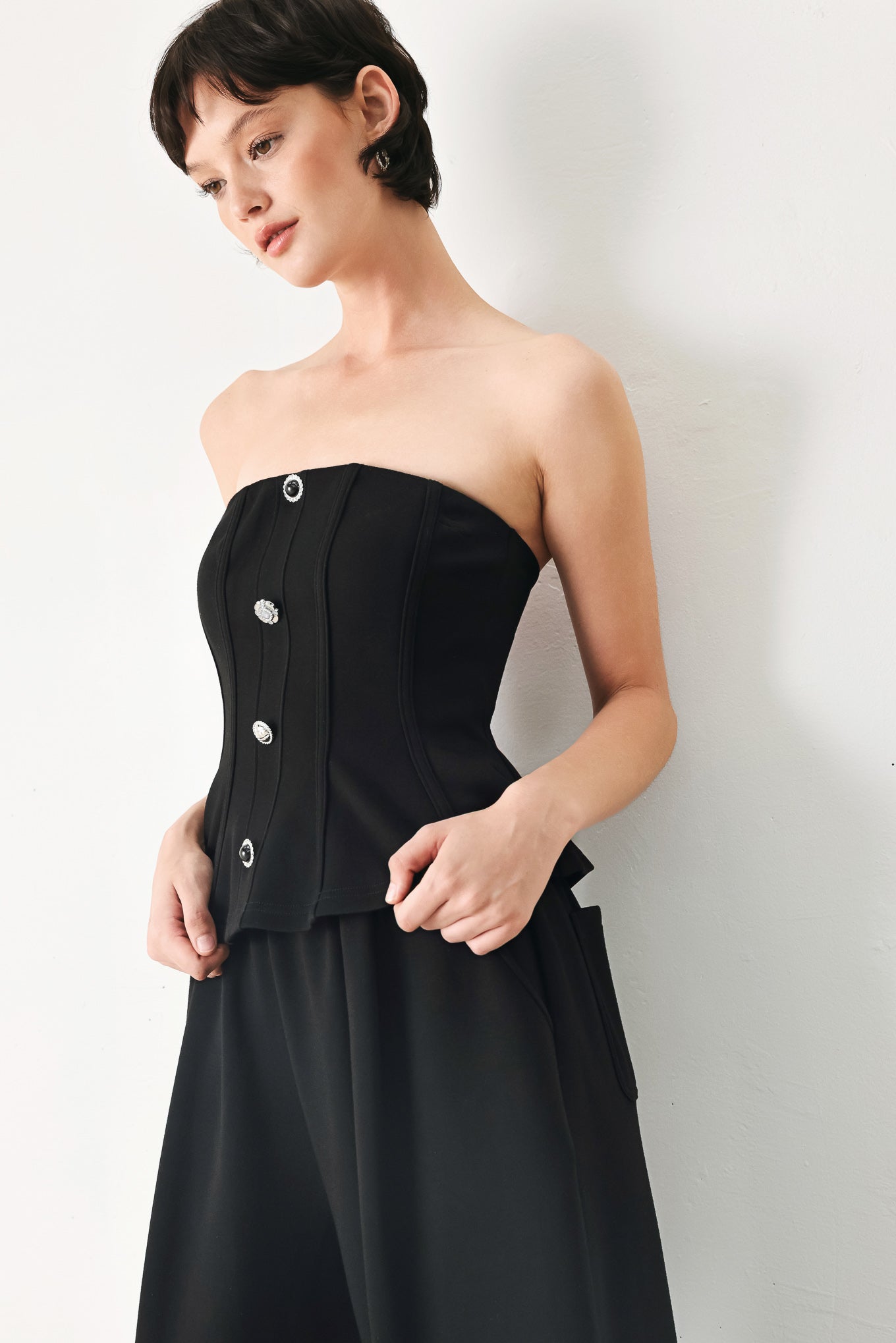 Woman wearing a black strapless tube top with buttons down the front | FREEMARKET