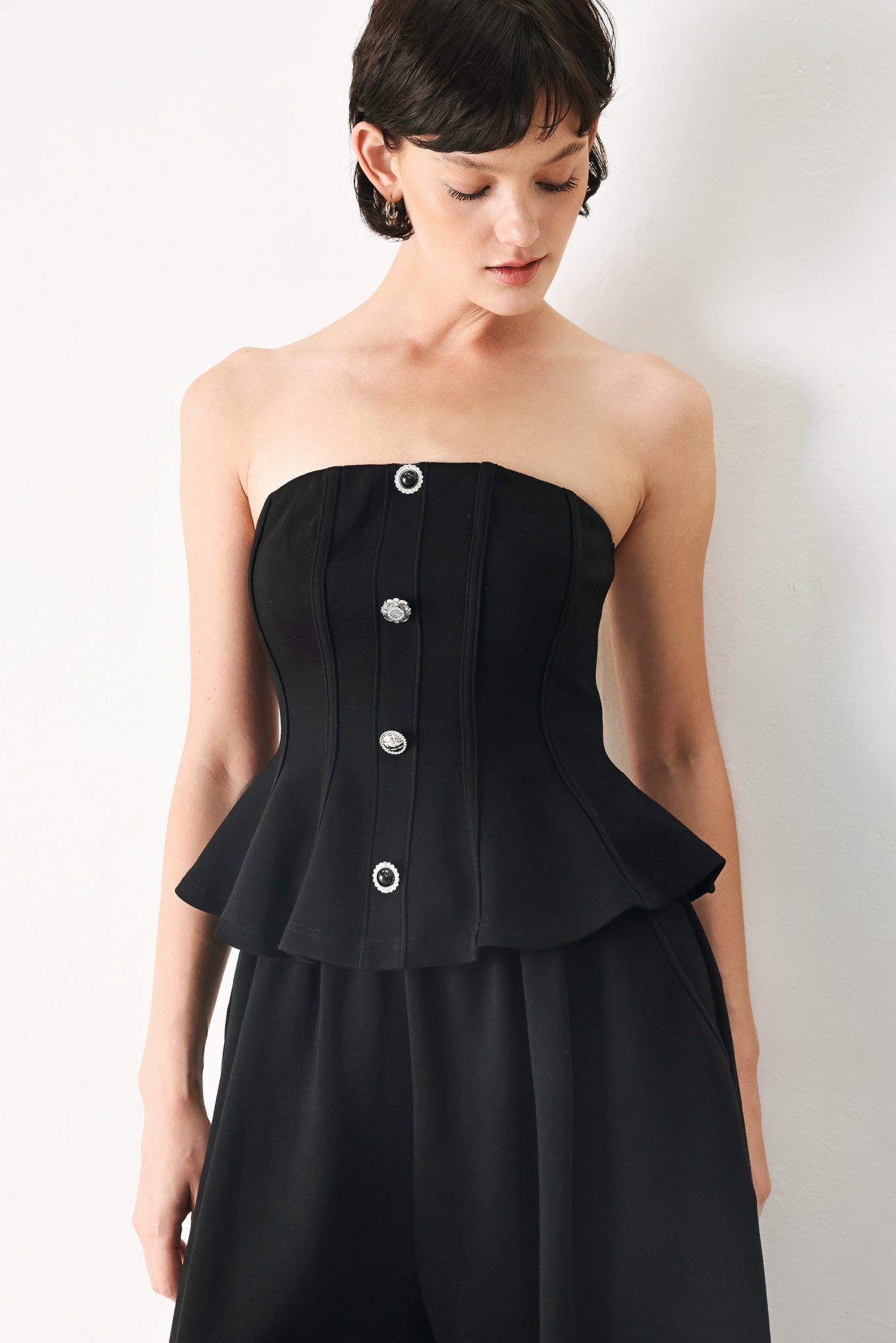 Woman wearing a black strapless tube top with buttons down the front | FREEMARKET