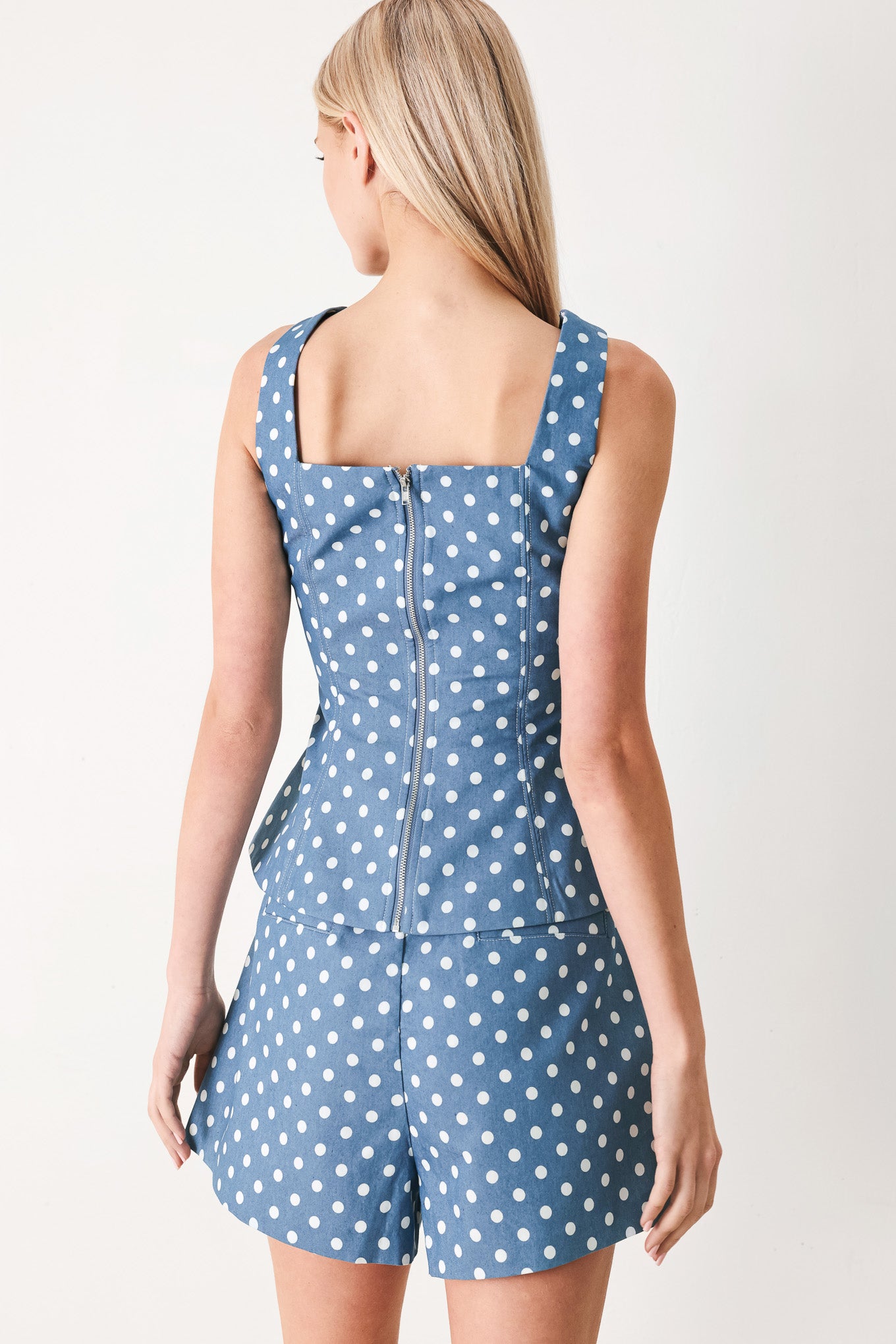Woman wearing a blue polka dot top featuring sweetheart neckline, sleeveless, front button detail, peplum and back zipper closure | FREEMARKET