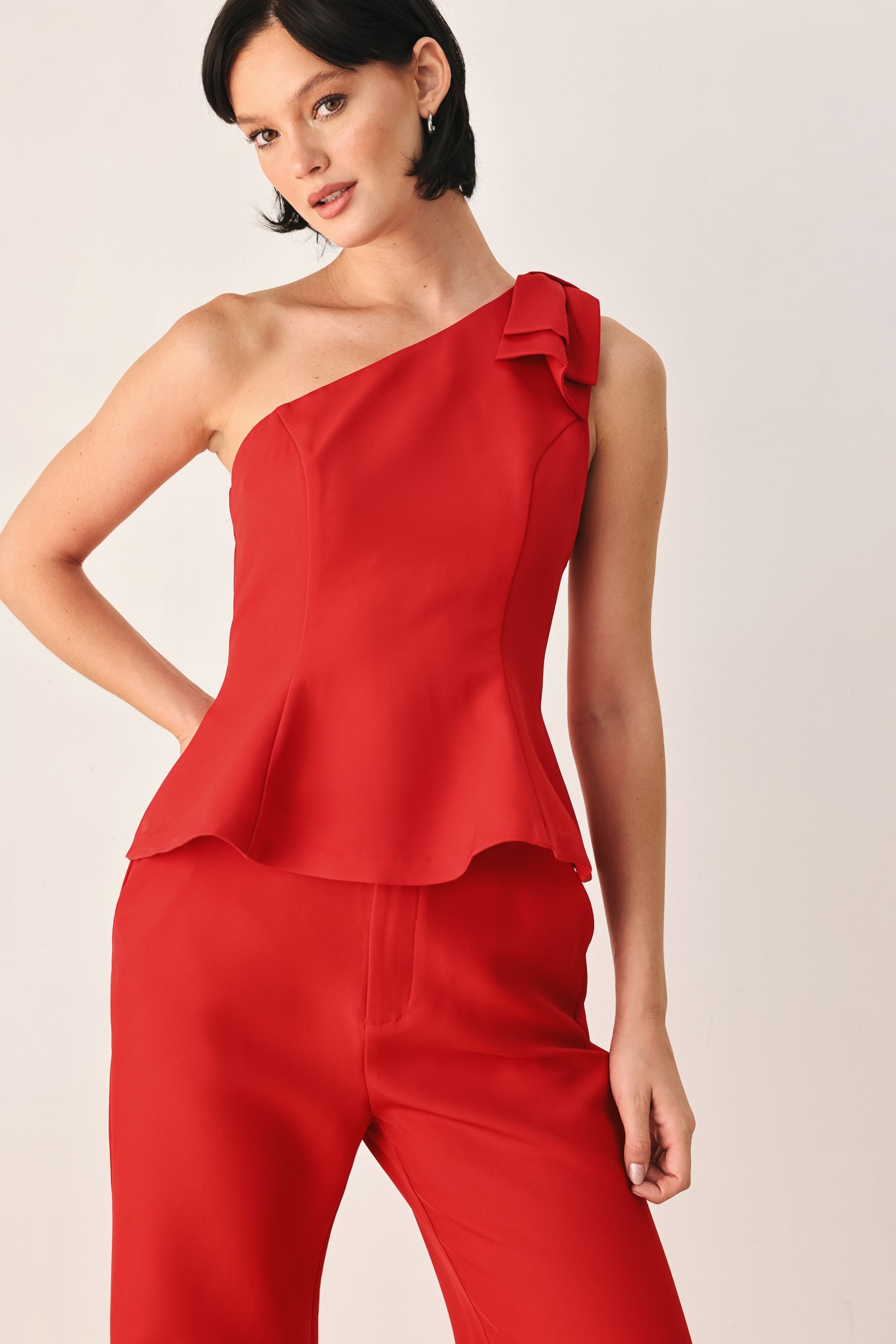 A woman modeling a bright red one-shoulder peplum top with a ruffled shoulder detail | FREEMARKET