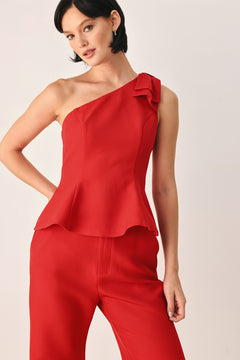 A woman modeling a bright red one-shoulder peplum top with a ruffled shoulder detail | FREEMARKET