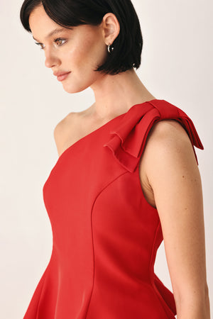 A woman modeling a bright red one-shoulder peplum top with a ruffled shoulder detail | FREEMARKET