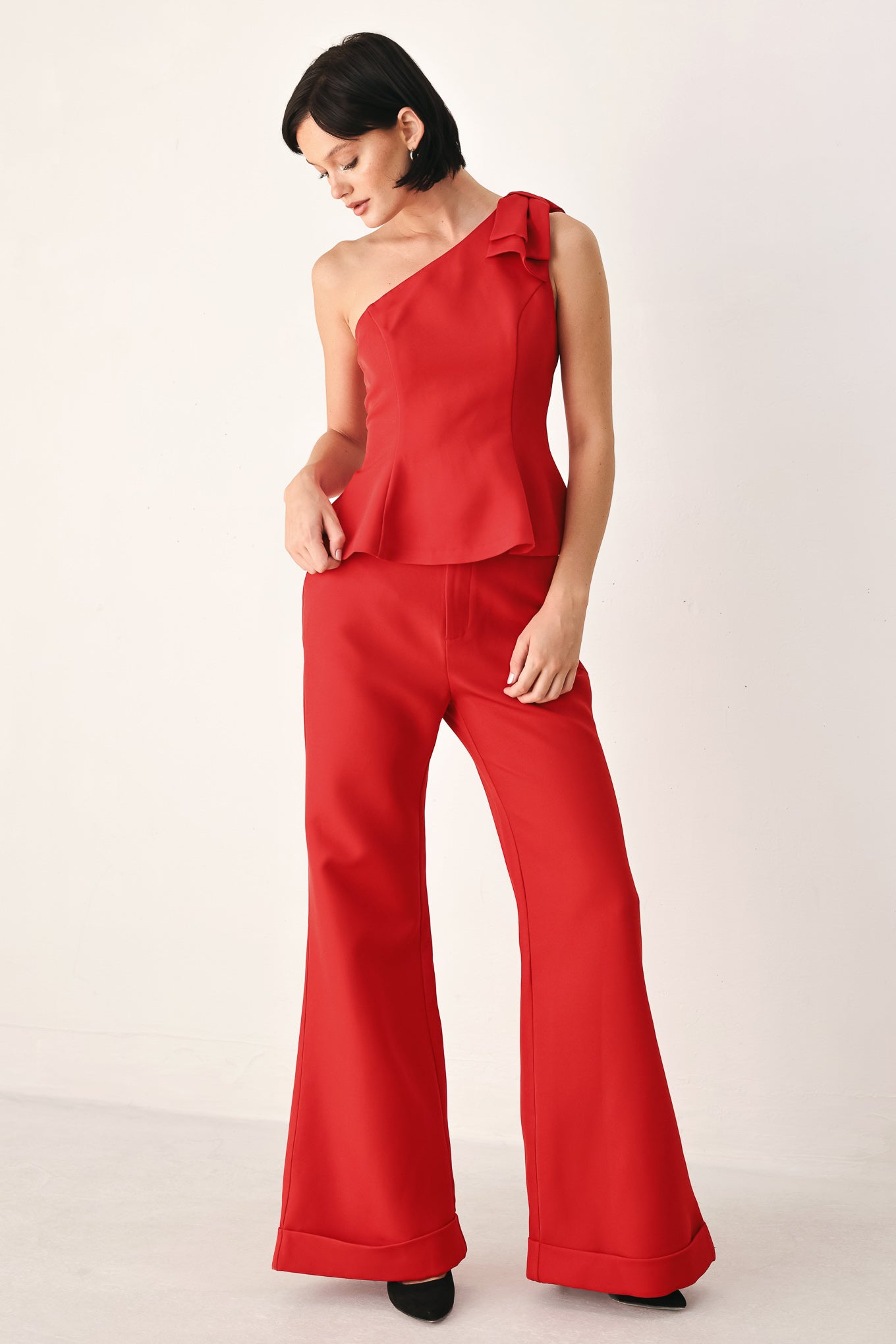 A woman modeling a bright red one-shoulder peplum top with a ruffled shoulder detail | FREEMARKET