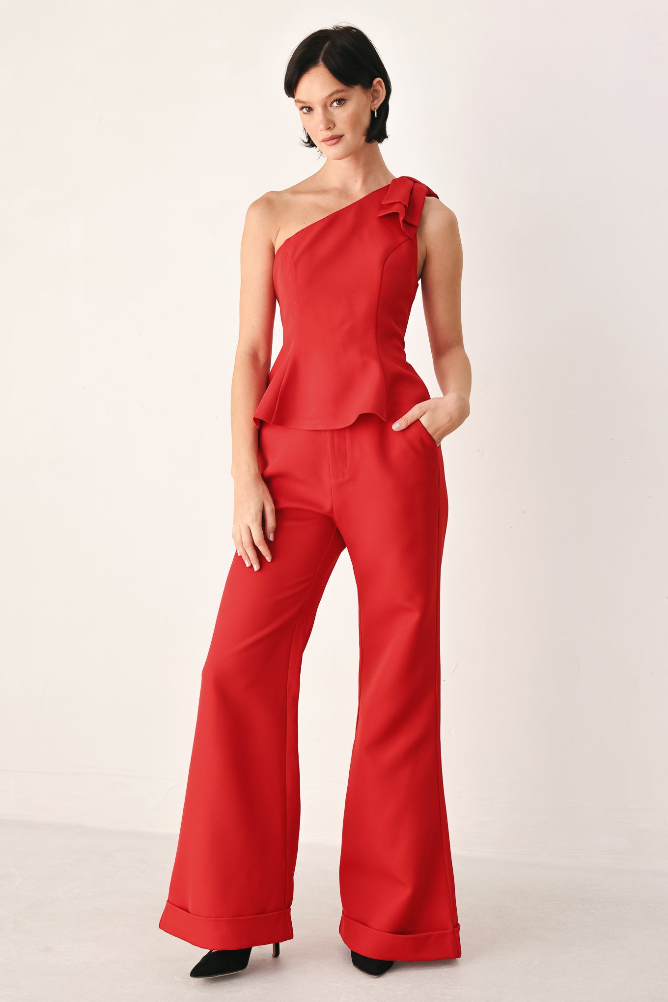 A woman modeling a bright red one-shoulder peplum top with a ruffled shoulder detail | FREEMARKET