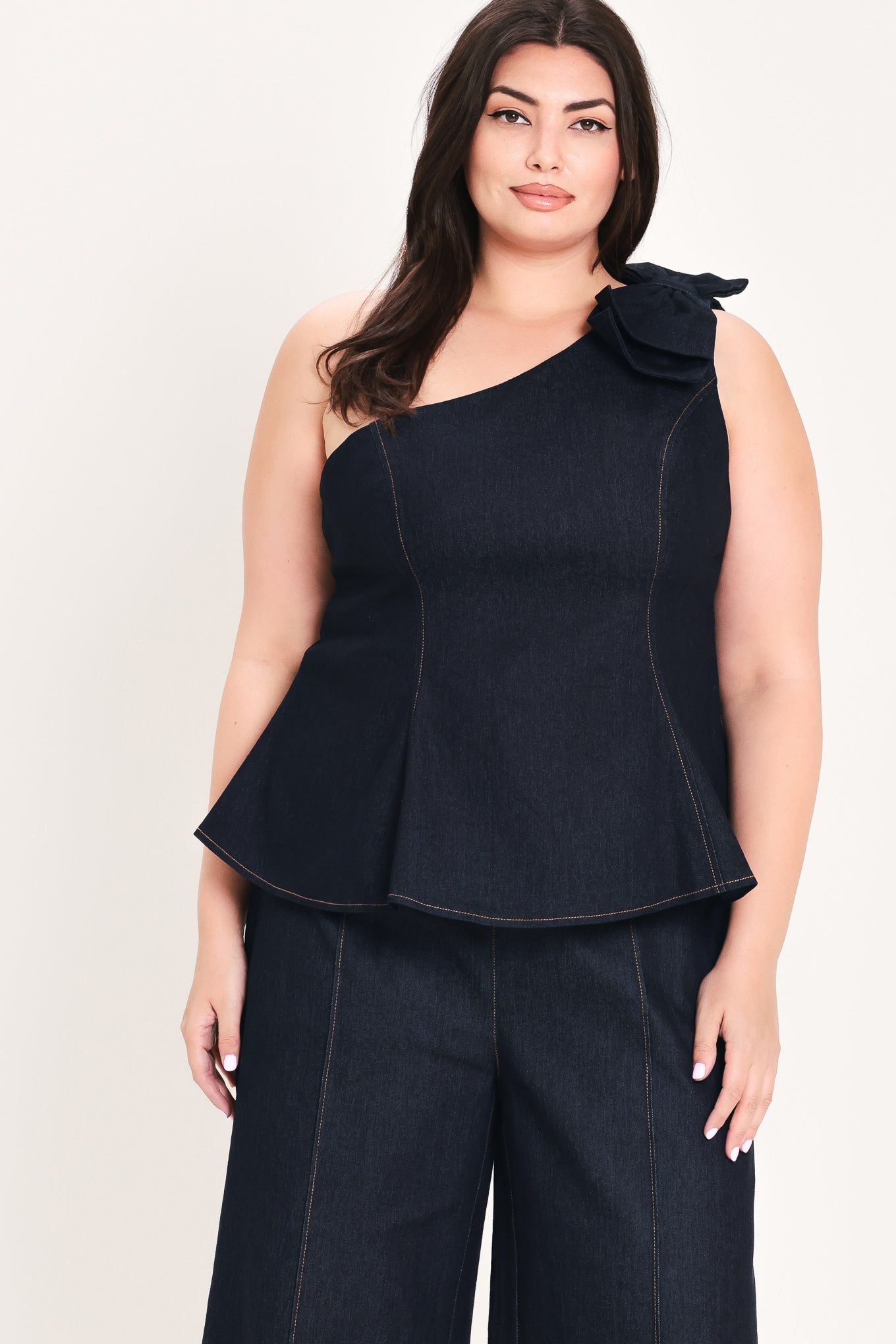 Woman wearing a dark blue denim one-shoulder peplum top with bow detail | FREEMARKET