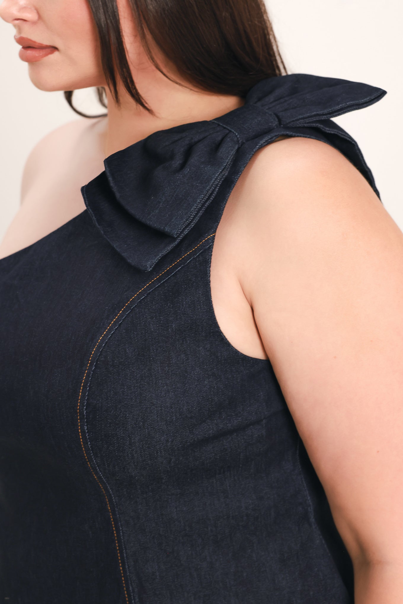 Woman wearing a dark blue denim one-shoulder peplum top with bow detail | FREEMARKET