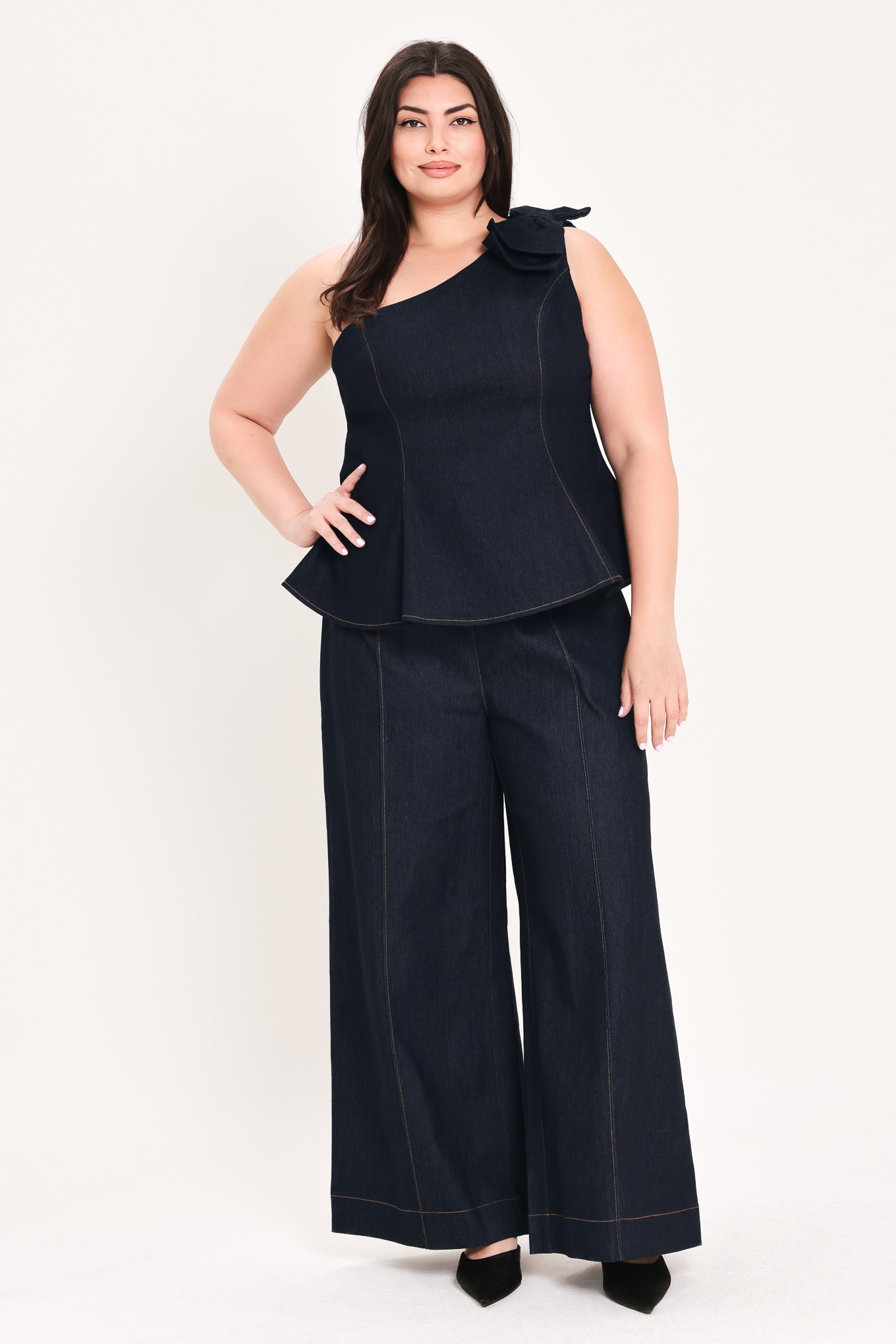 Woman wearing a dark blue denim one-shoulder peplum top with bow detail | FREEMARKET