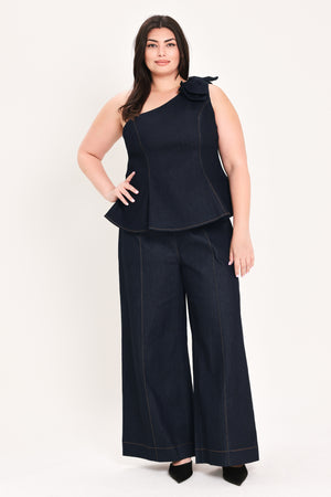 Woman wearing a dark blue denim one-shoulder peplum top with bow detail | FREEMARKET