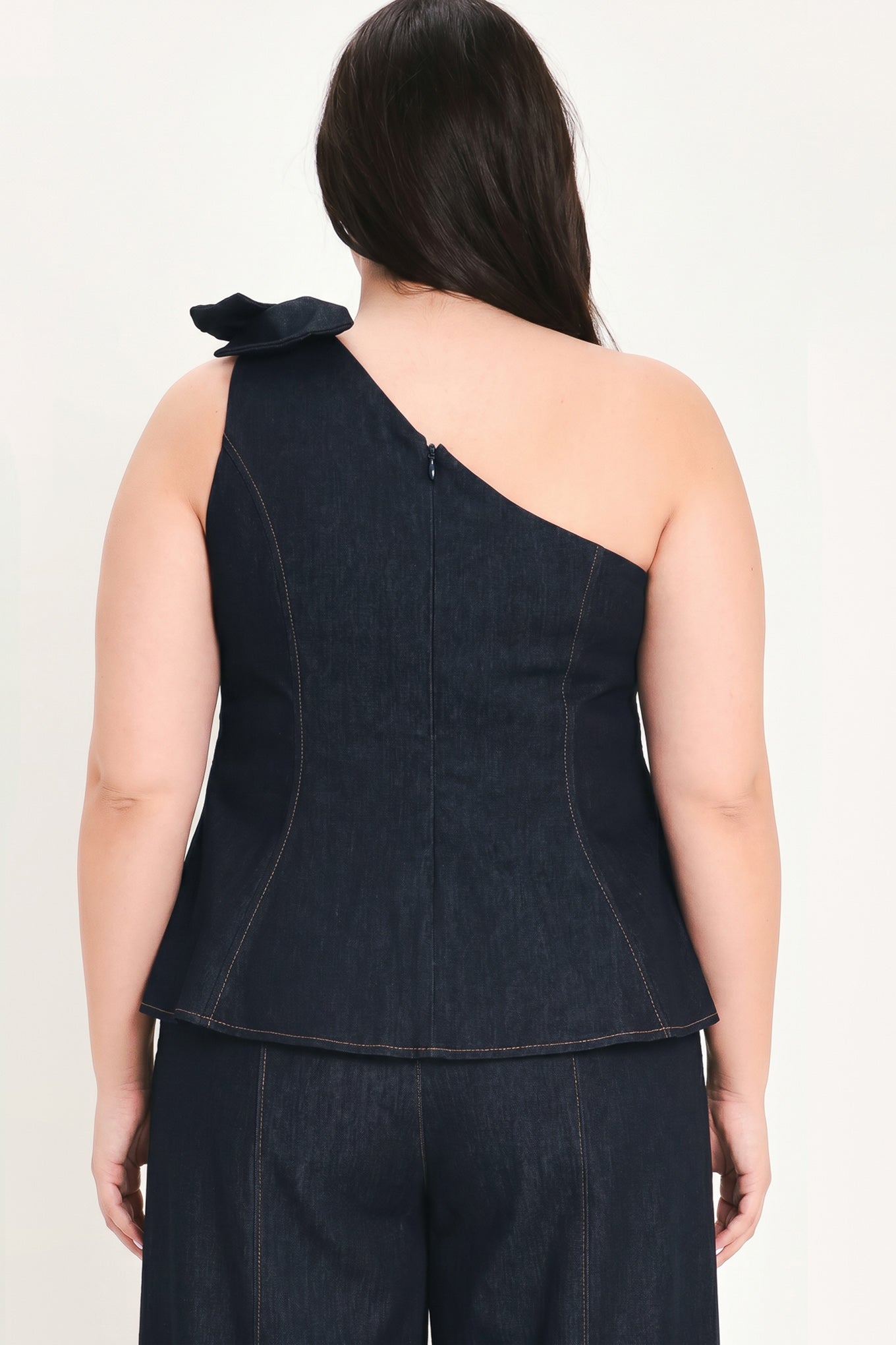 Woman wearing a dark blue denim one-shoulder peplum top with bow detail | FREEMARKET
