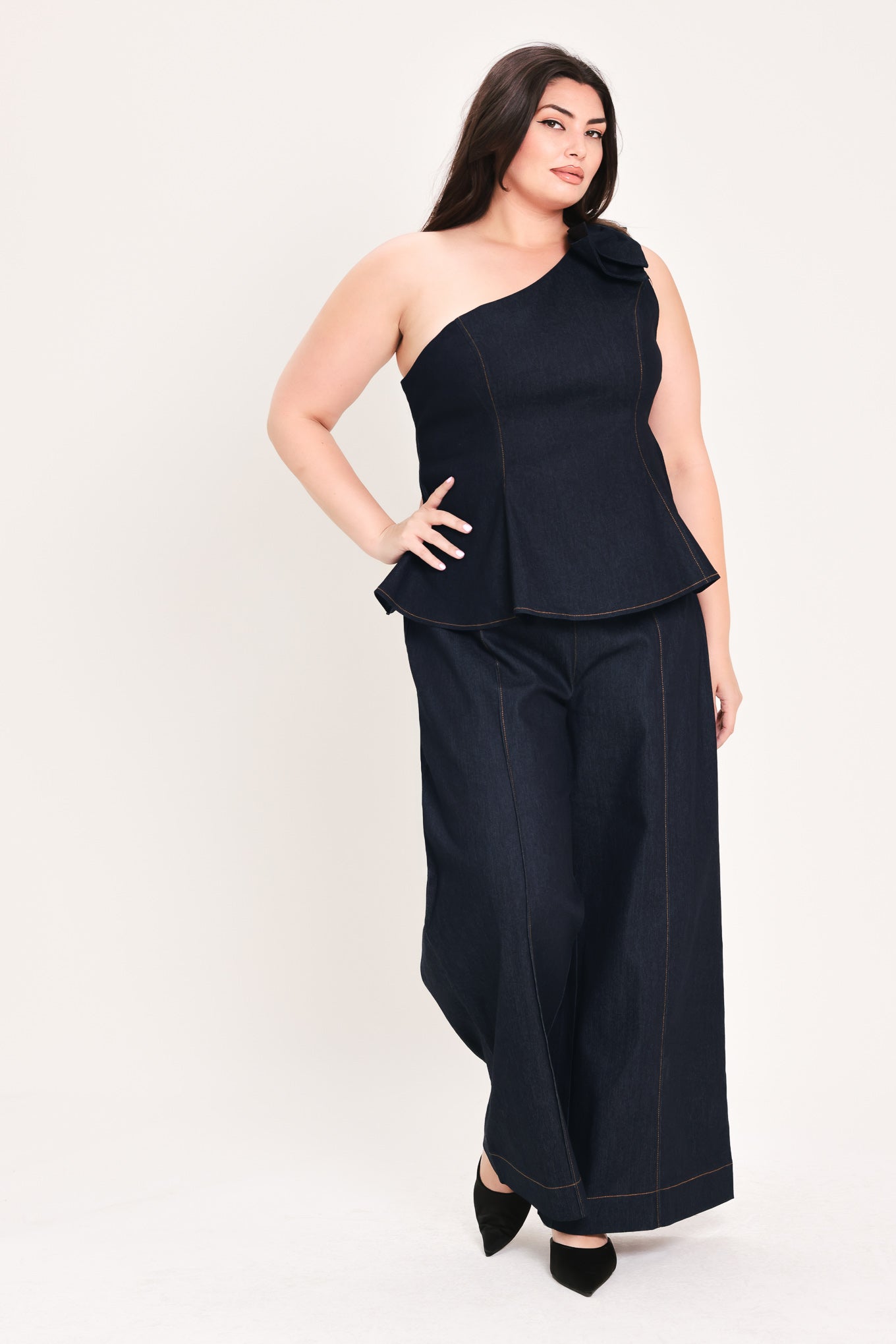 Woman wearing a dark blue denim one-shoulder peplum top with bow detail | FREEMARKET