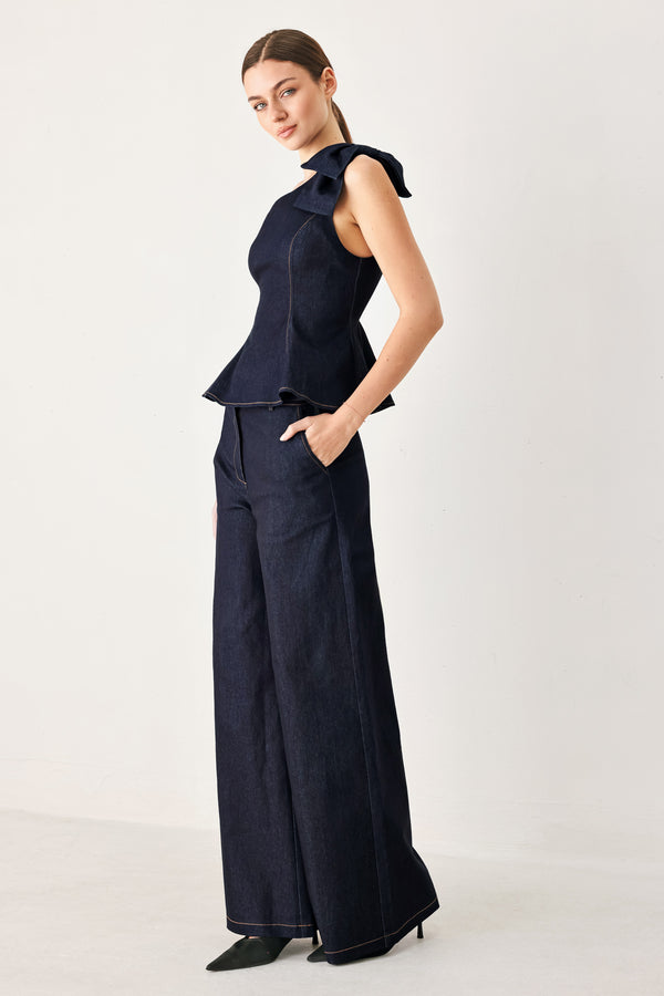 Woman wearing a dark blue denim one-shoulder peplum top with bow detail | Flying Tomato