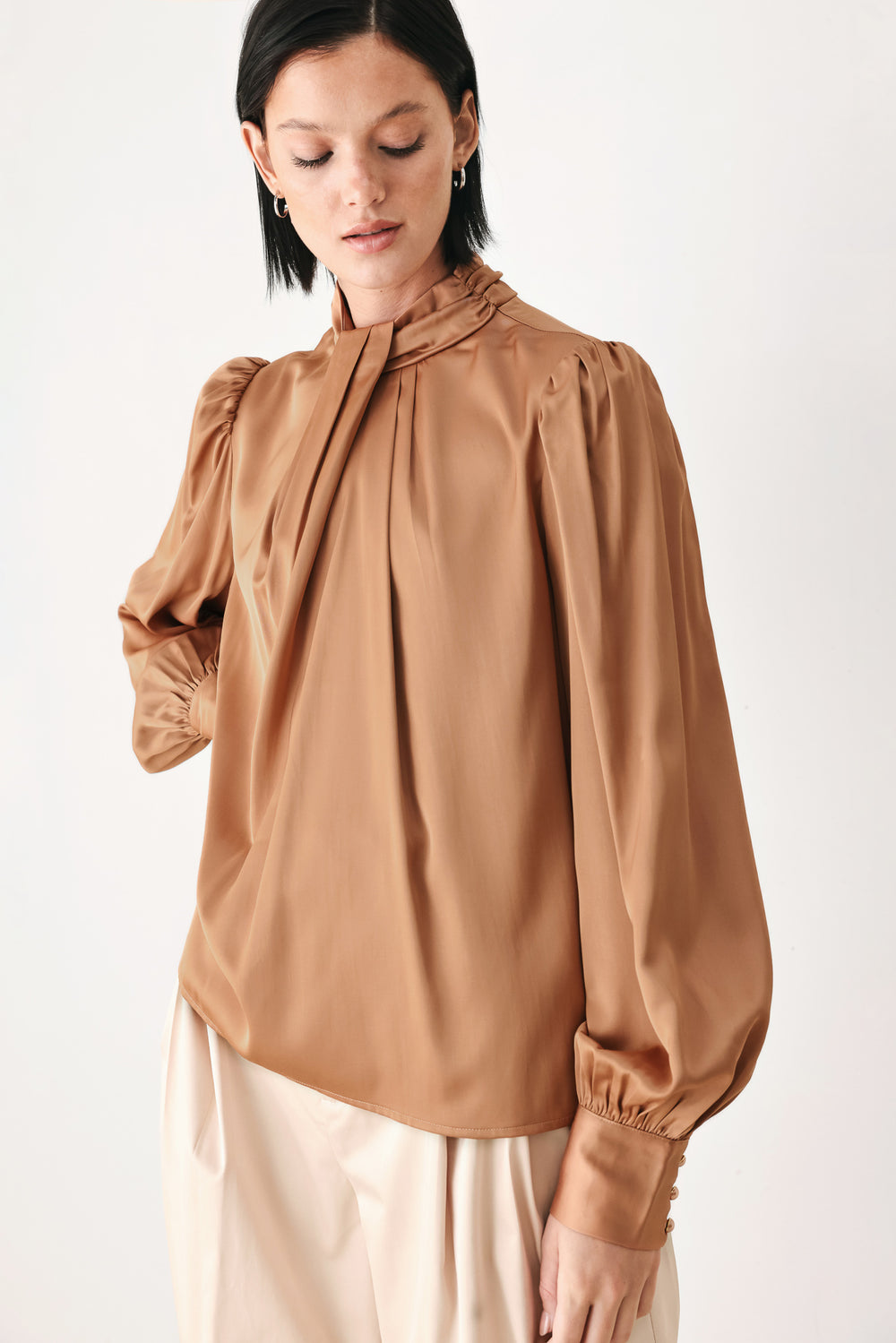 A woman wearing a bronze long-sleeve blouse with a gathered high neck and voluminous sleeves | FREEMARKET