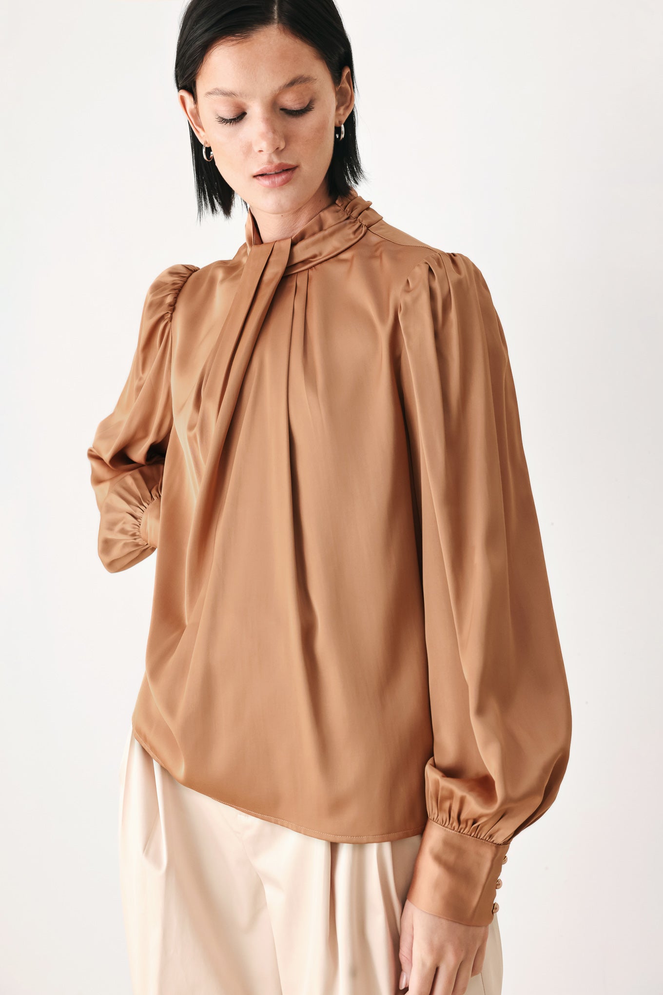 A woman wearing a bronze long-sleeve blouse with a gathered high neck and voluminous sleeves | FREEMARKET