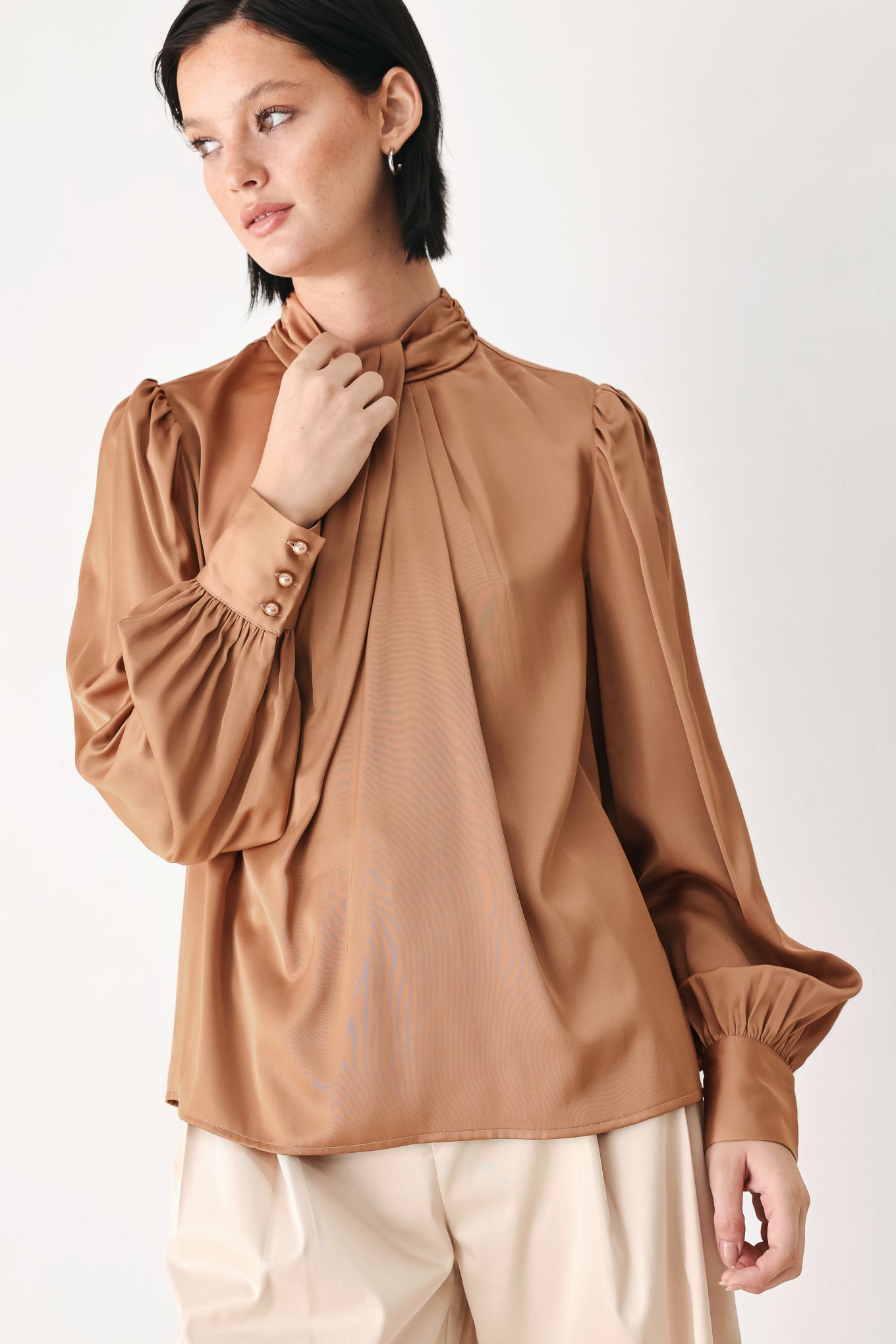 A woman wearing a bronze long-sleeve blouse with a gathered high neck and voluminous sleeves | FREEMARKET