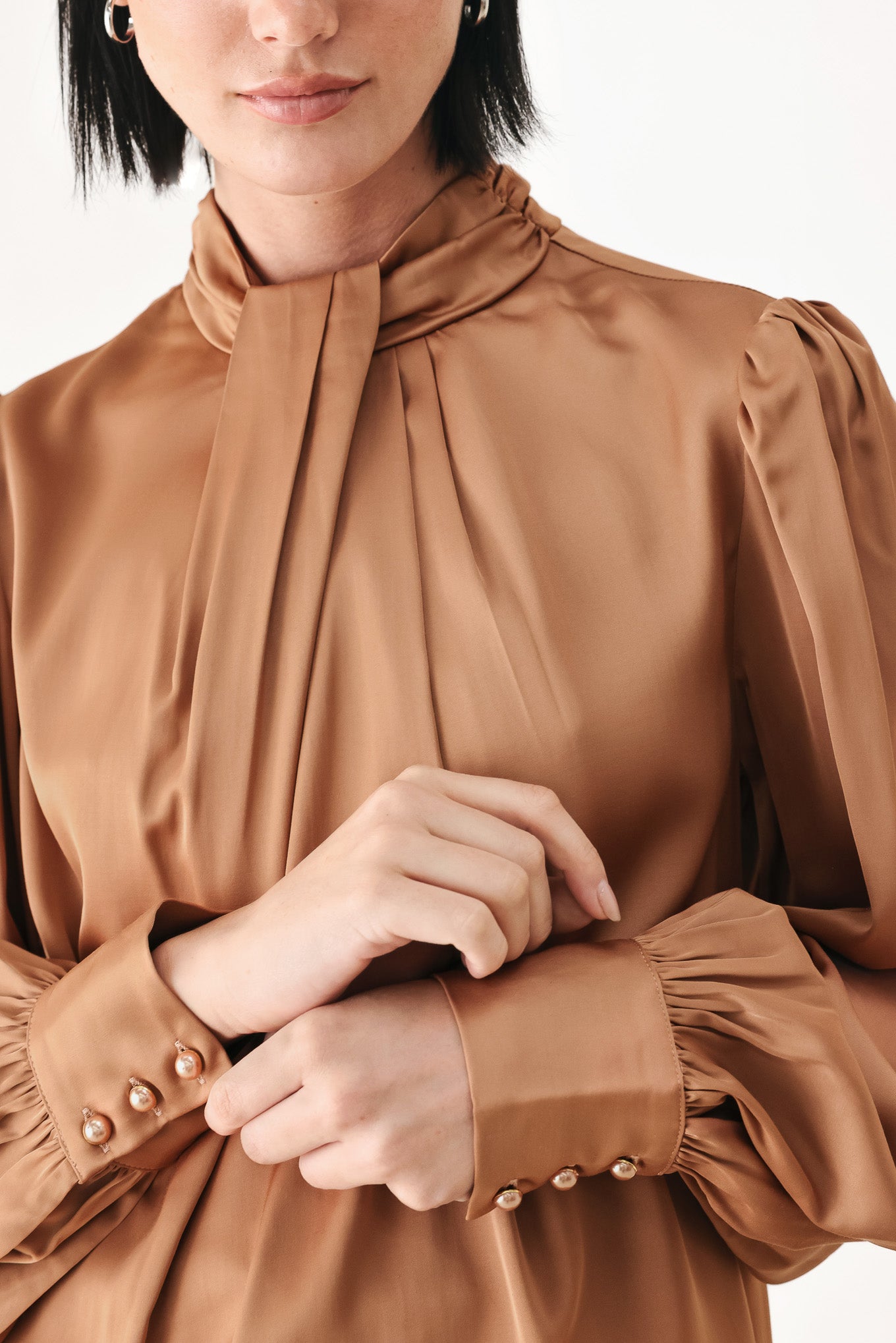 A woman wearing a bronze long-sleeve blouse with a gathered high neck and voluminous sleeves | FREEMARKET