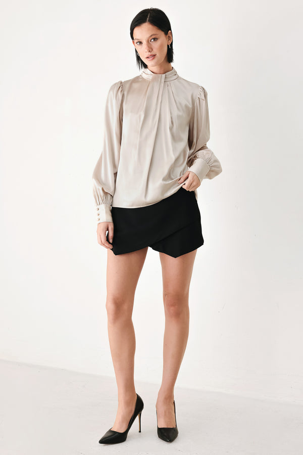 A woman wearing a champagne ivory long-sleeve blouse with a gathered high neck and voluminous sleeves | FREEMARKET