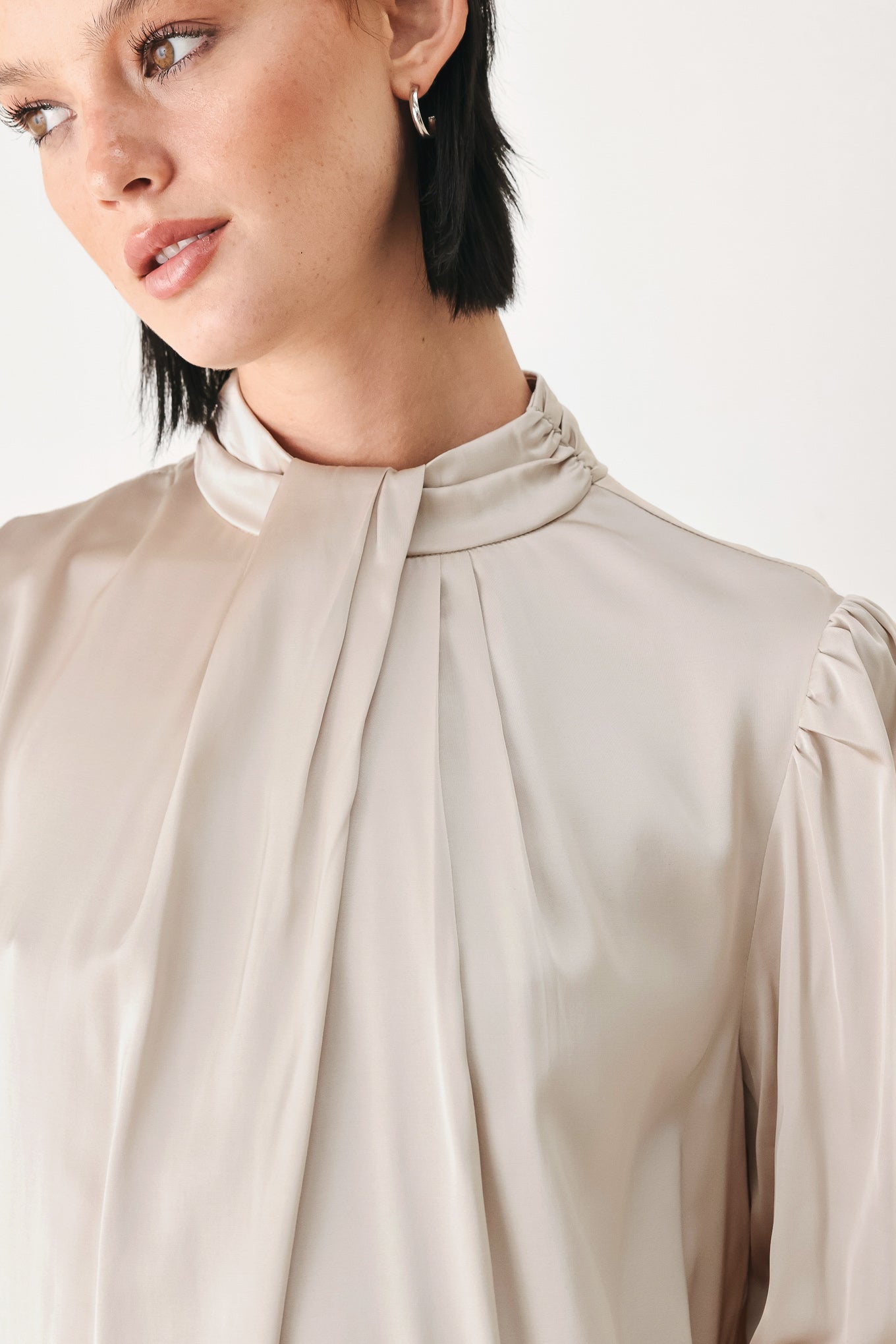 A woman wearing a champagne ivory long-sleeve blouse with a gathered high neck and voluminous sleeves | FREEMARKET
