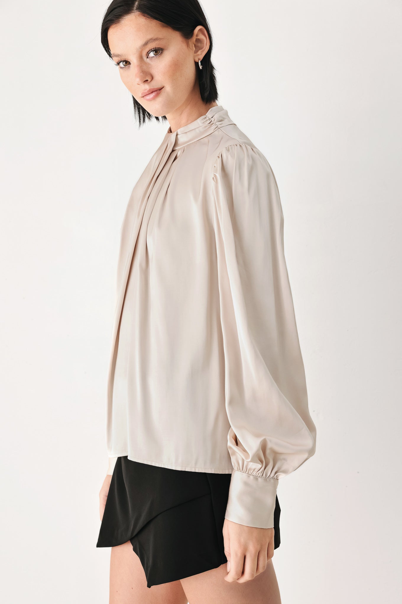 A woman wearing a champagne ivory long-sleeve blouse with a gathered high neck and voluminous sleeves | FREEMARKET