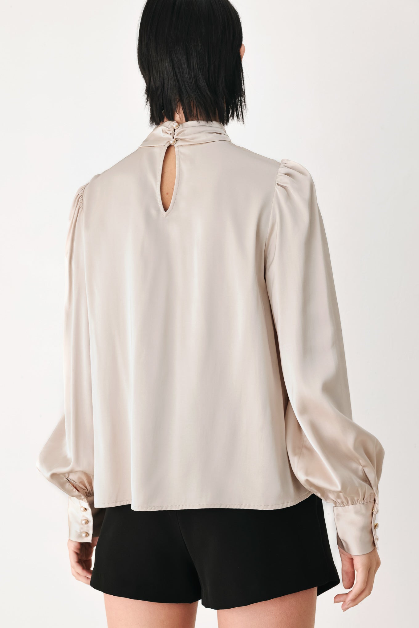 A woman wearing a champagne ivory long-sleeve blouse with a gathered high neck and voluminous sleeves | FREEMARKET