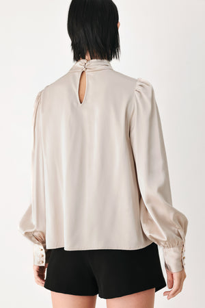 A woman wearing a champagne ivory long-sleeve blouse with a gathered high neck and voluminous sleeves | FREEMARKET