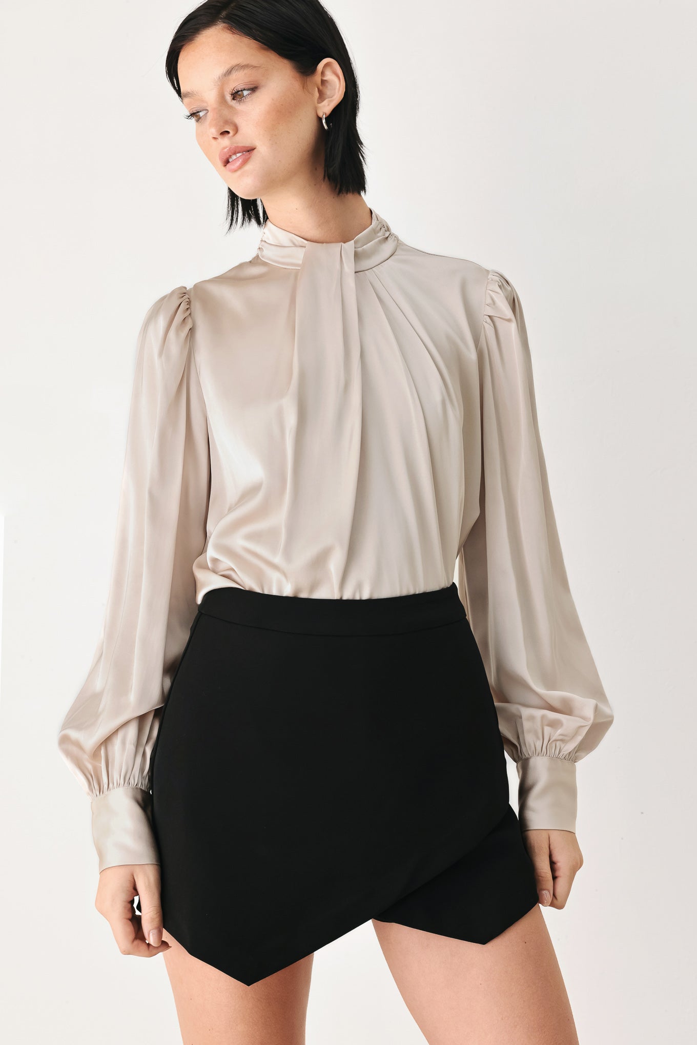 A woman wearing a champagne ivory long-sleeve blouse with a gathered high neck and voluminous sleeves | FREEMARKET