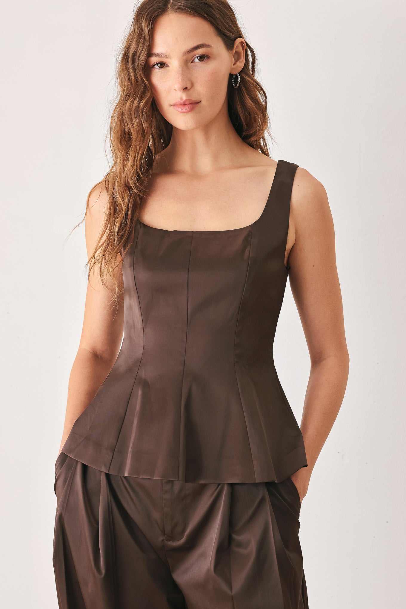 A woman modeling a dark brown satin-like sleeveless top with a square neckline and structured peplum waist | FREEMARKET