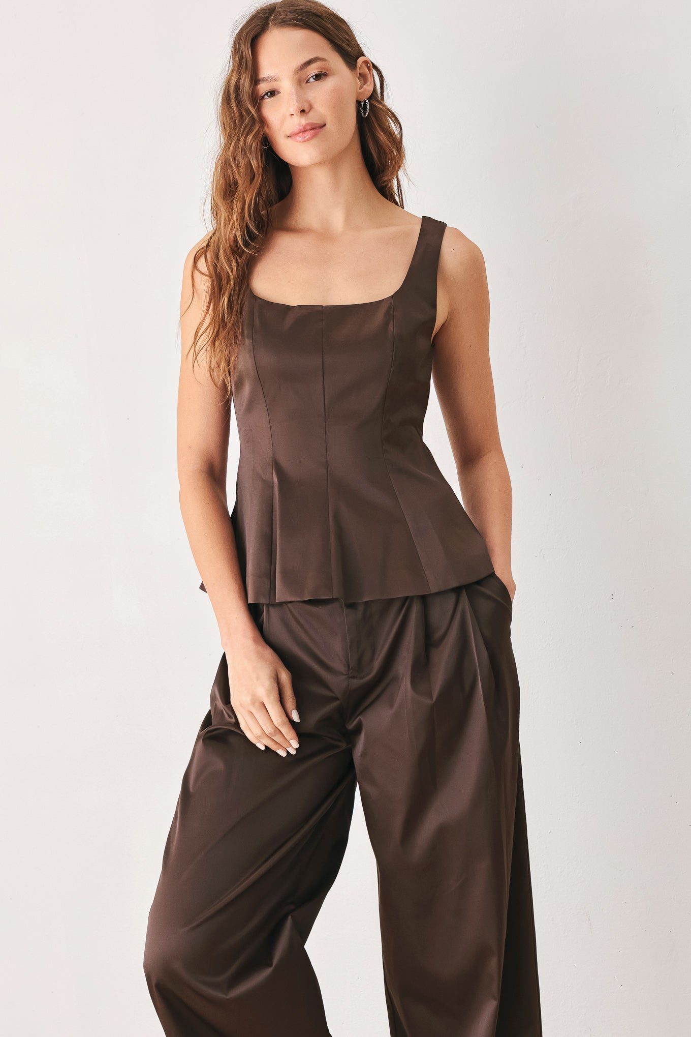 A woman modeling a dark brown satin-like sleeveless top with a square neckline and structured peplum waist | FREEMARKET