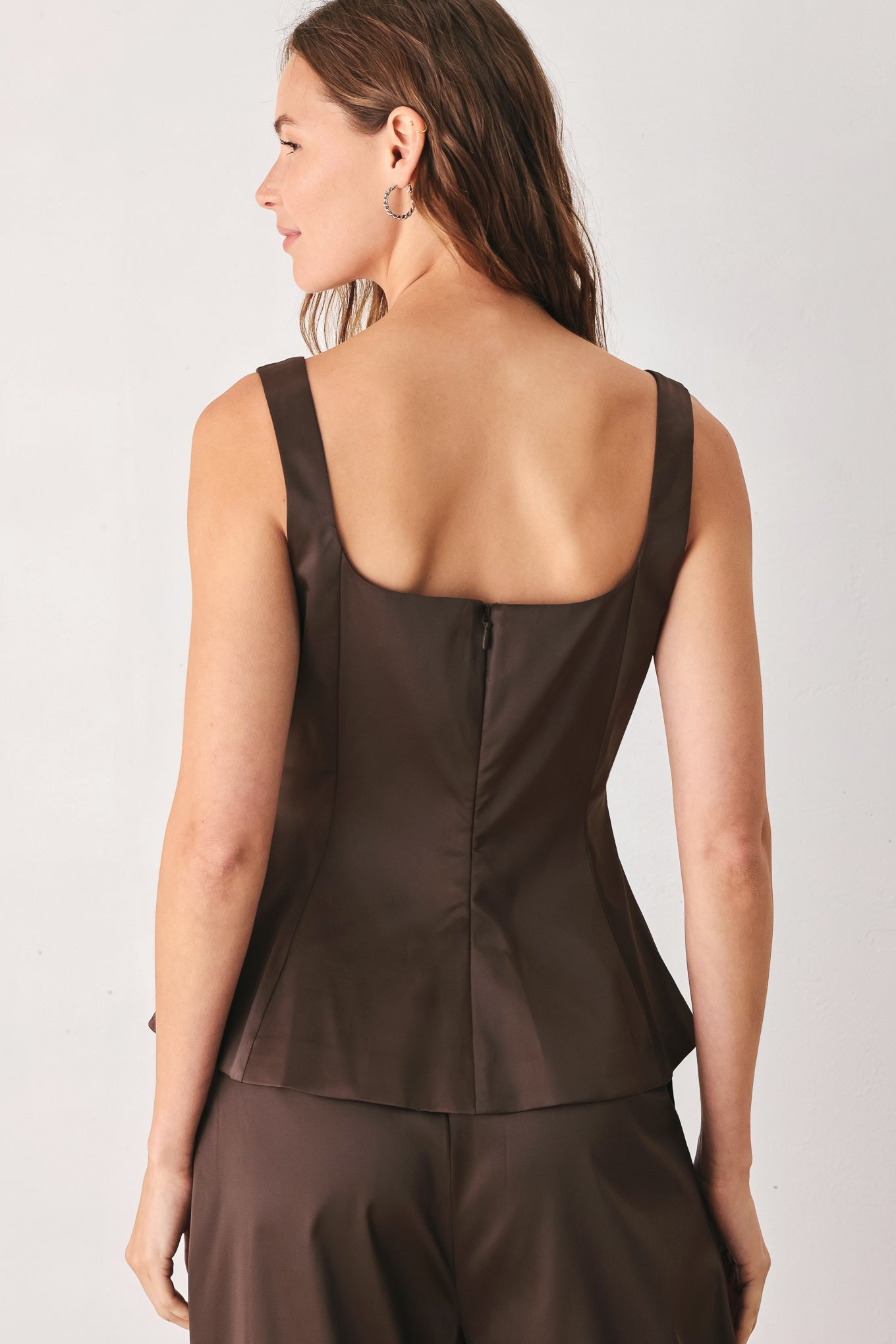 A woman modeling a dark brown satin-like sleeveless top with a square neckline and structured peplum waist | FREEMARKET