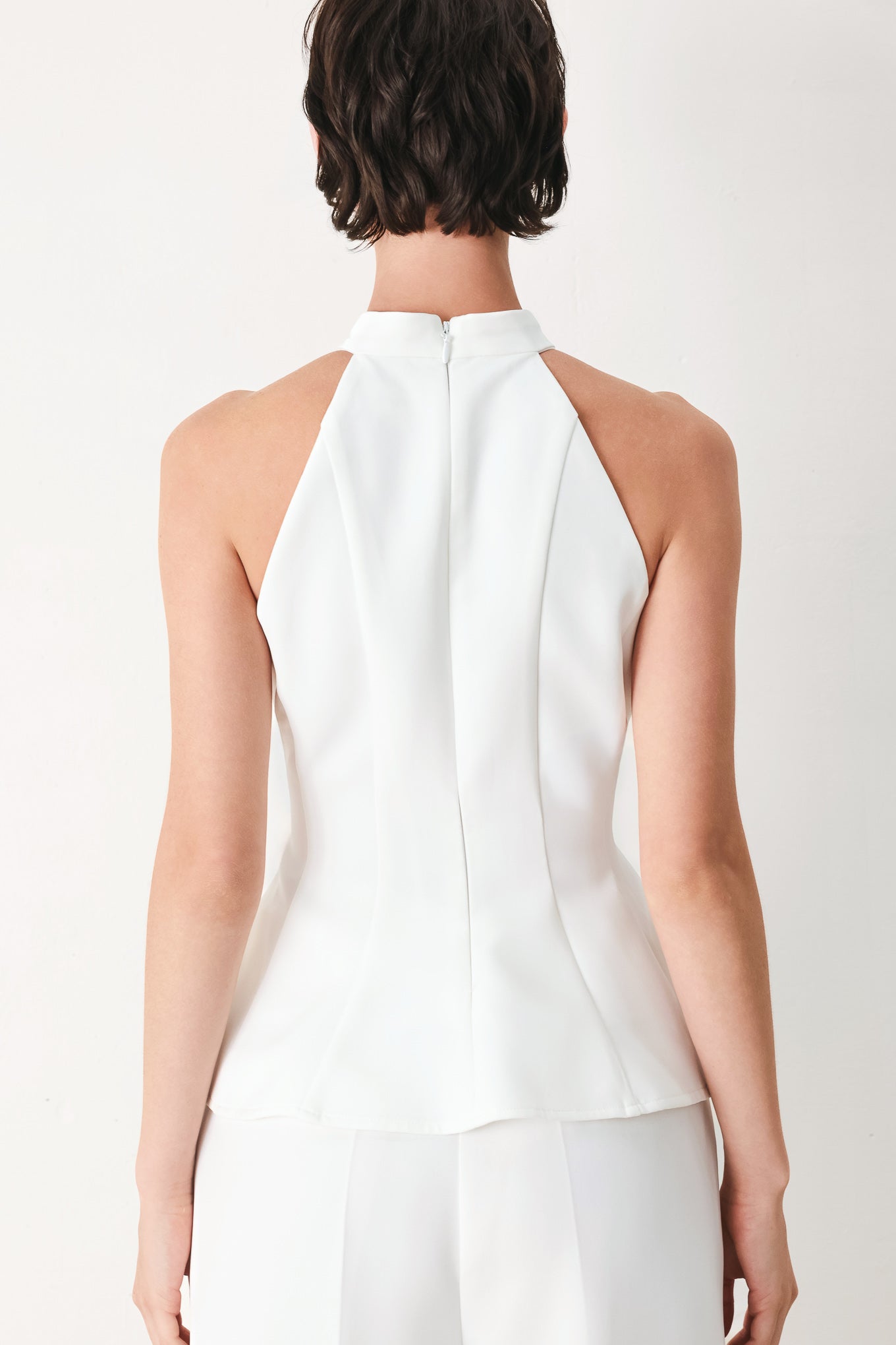 Woman wearing a white peplum top featuring halter neckline and back zipper closure | FREEMARKET
