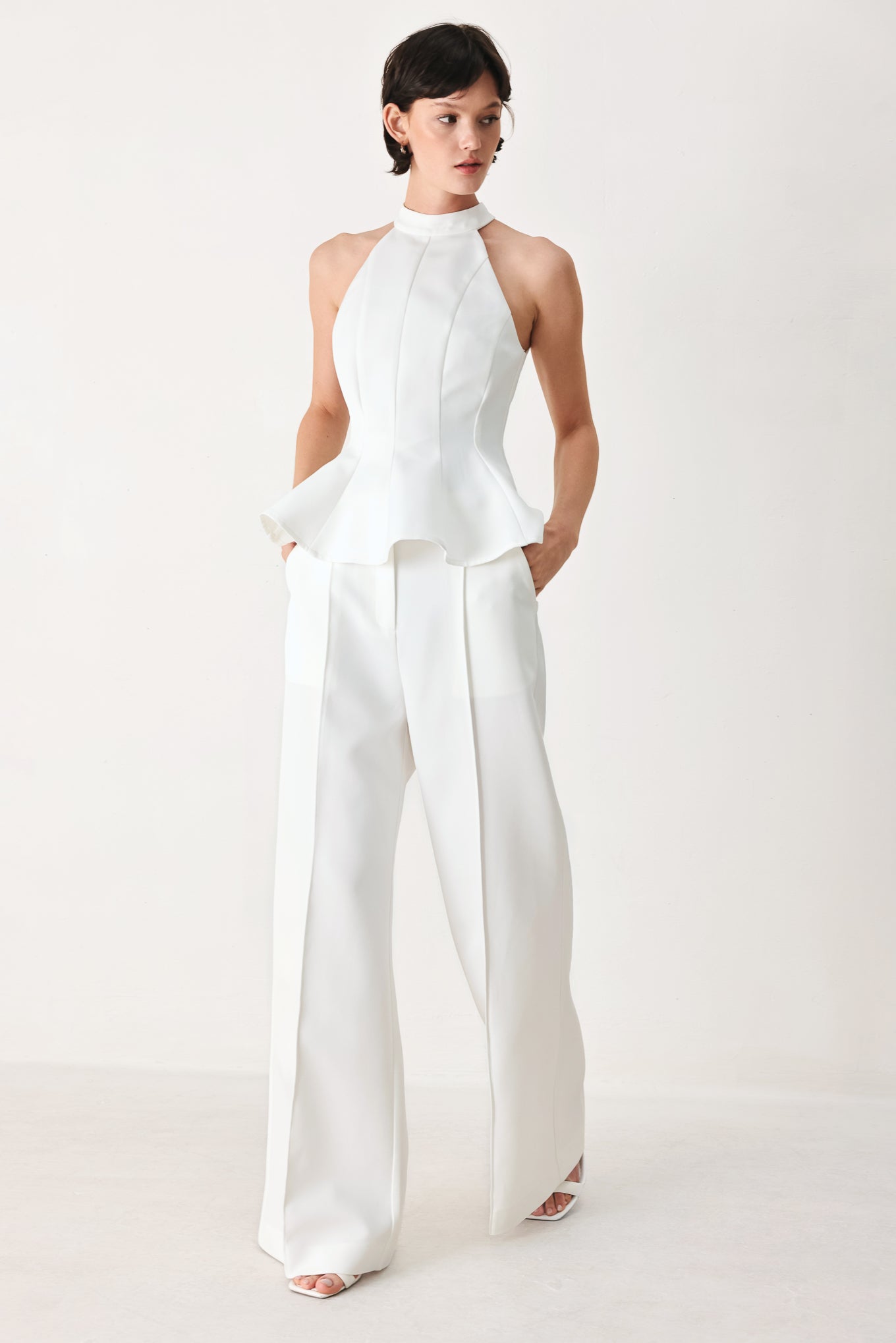 Woman wearing a white peplum top featuring halter neckline and back zipper closure | FREEMARKET