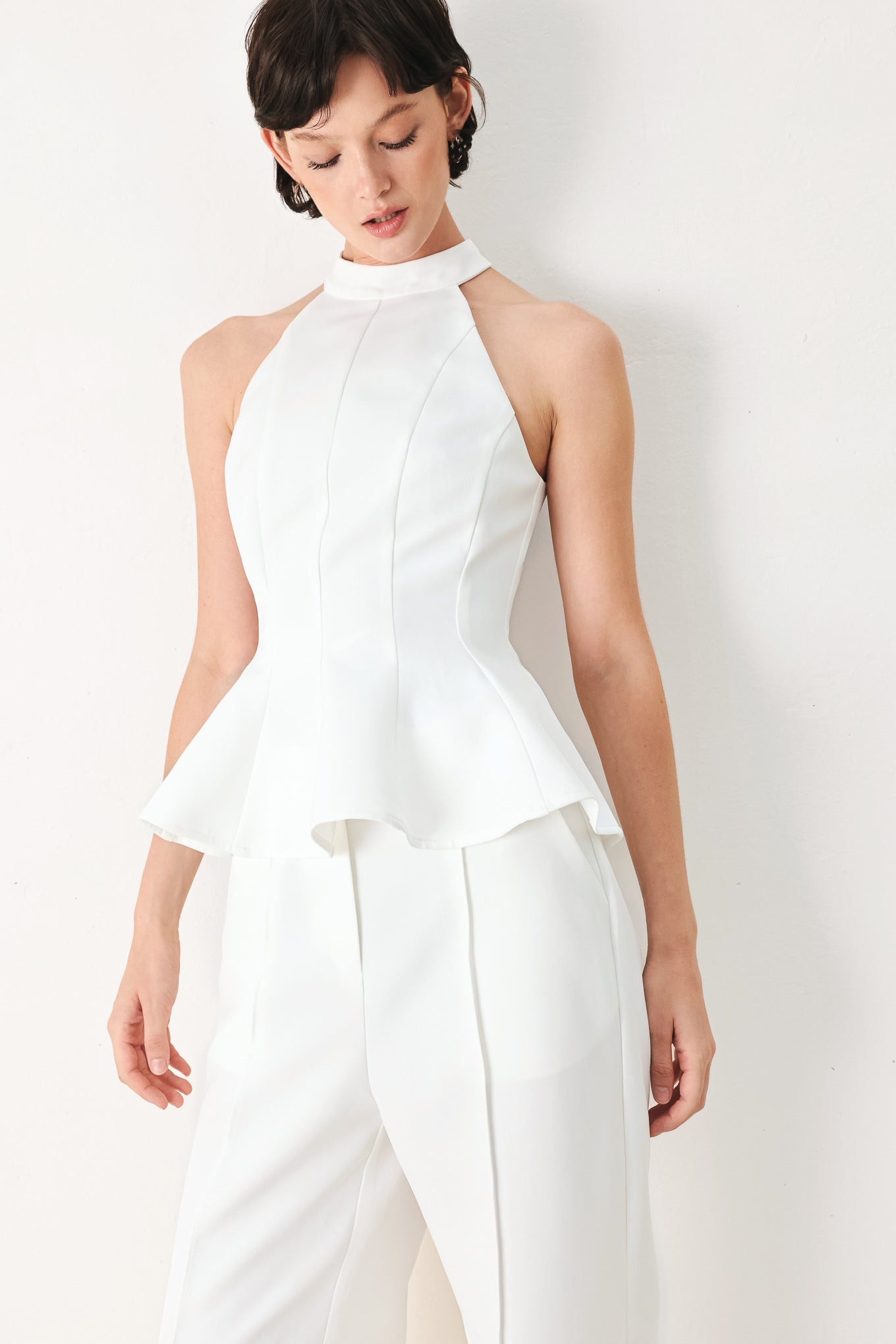 Woman wearing a white peplum top featuring halter neckline and back zipper closure | FREEMARKET
