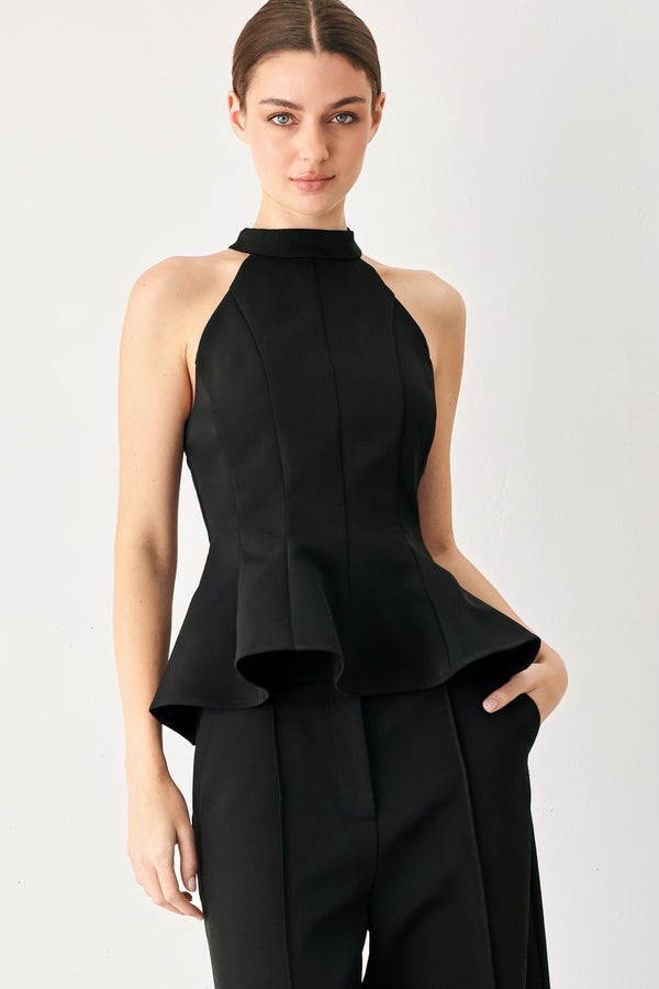 Woman wearing a black solid woven top with halter neckline, peplum and back zipper closure | FREEMARKET