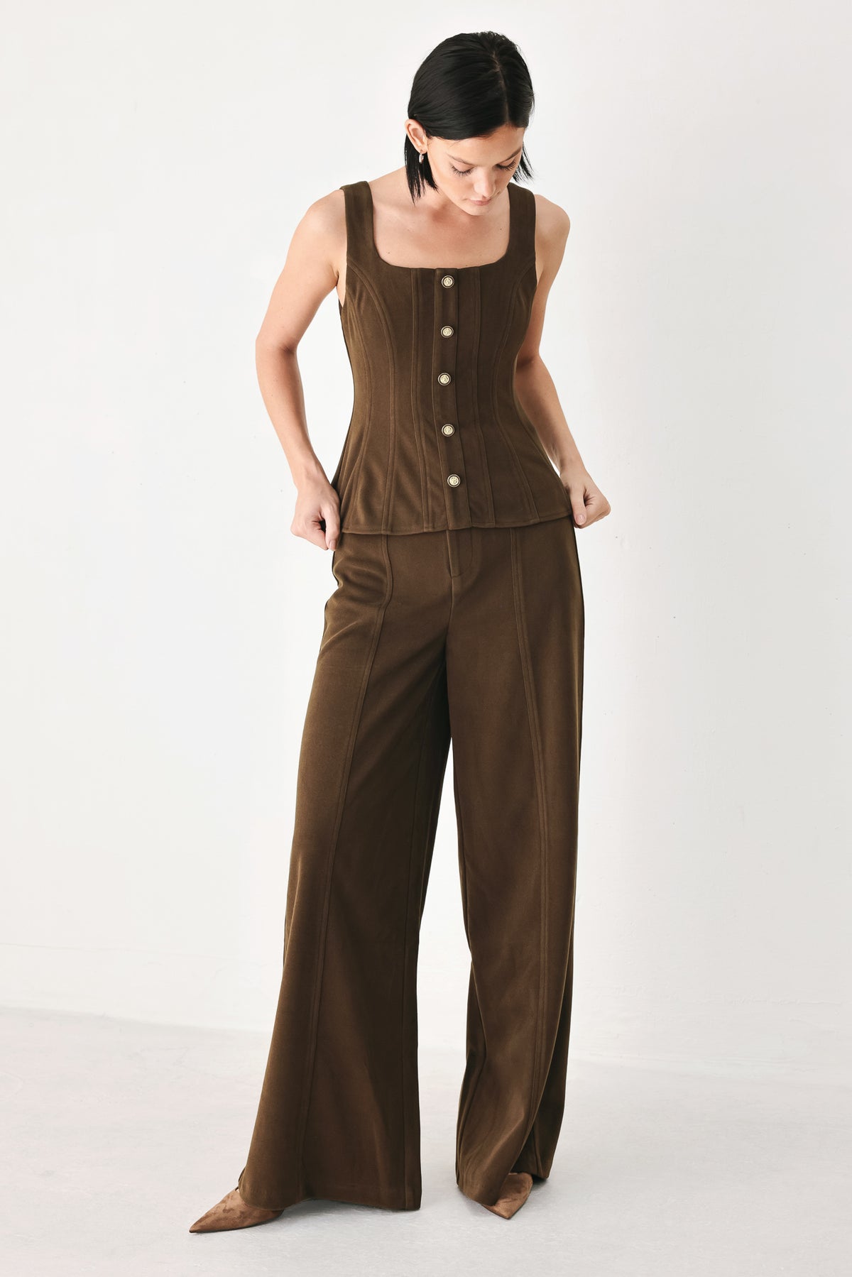 A woman wearing a brown sleeveless vest with a square neckline, front button closure, and vertical seam detailing | FREEMARKET
