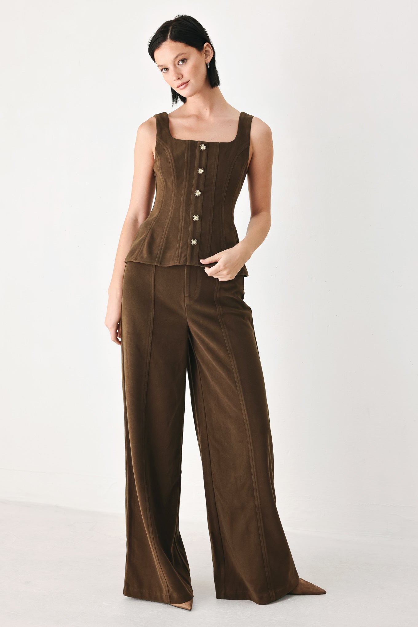 A woman wearing a brown sleeveless vest with a square neckline, front button closure, and vertical seam detailing | FREEMARKET