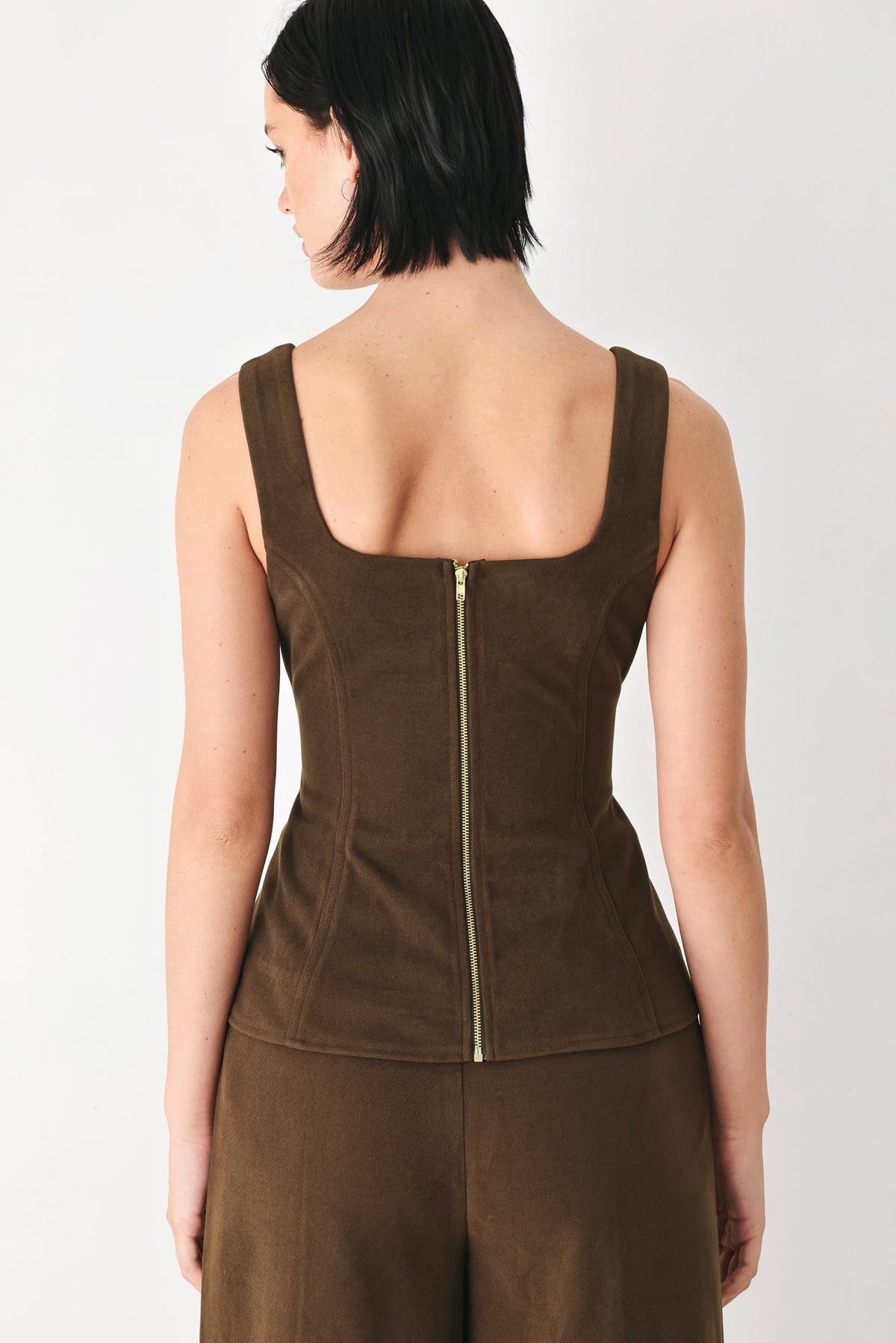 A woman wearing a brown sleeveless vest with a square neckline, front button closure, and vertical seam detailing | FREEMARKET