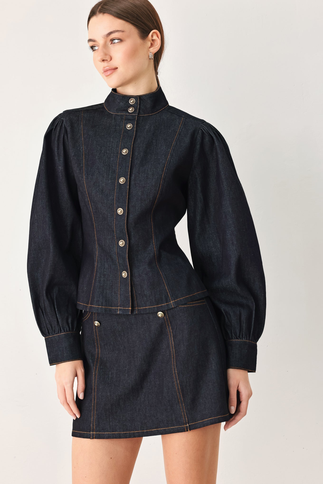 Woman wearing lightweight dark denim top with high neckline, long sleeve, front button down and peplum | FREEMARKET