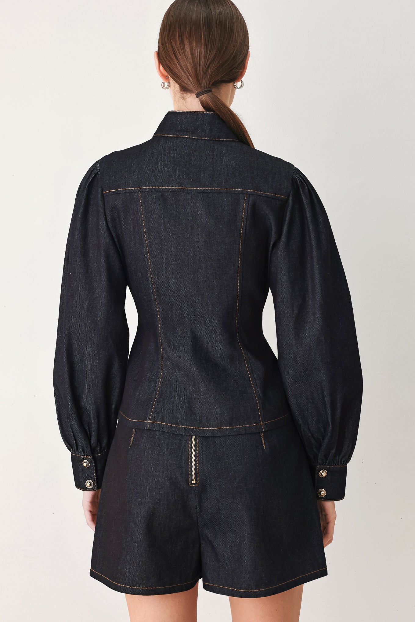 Woman wearing lightweight dark denim top with high neckline, long sleeve, front button down and peplum | FREEMARKET